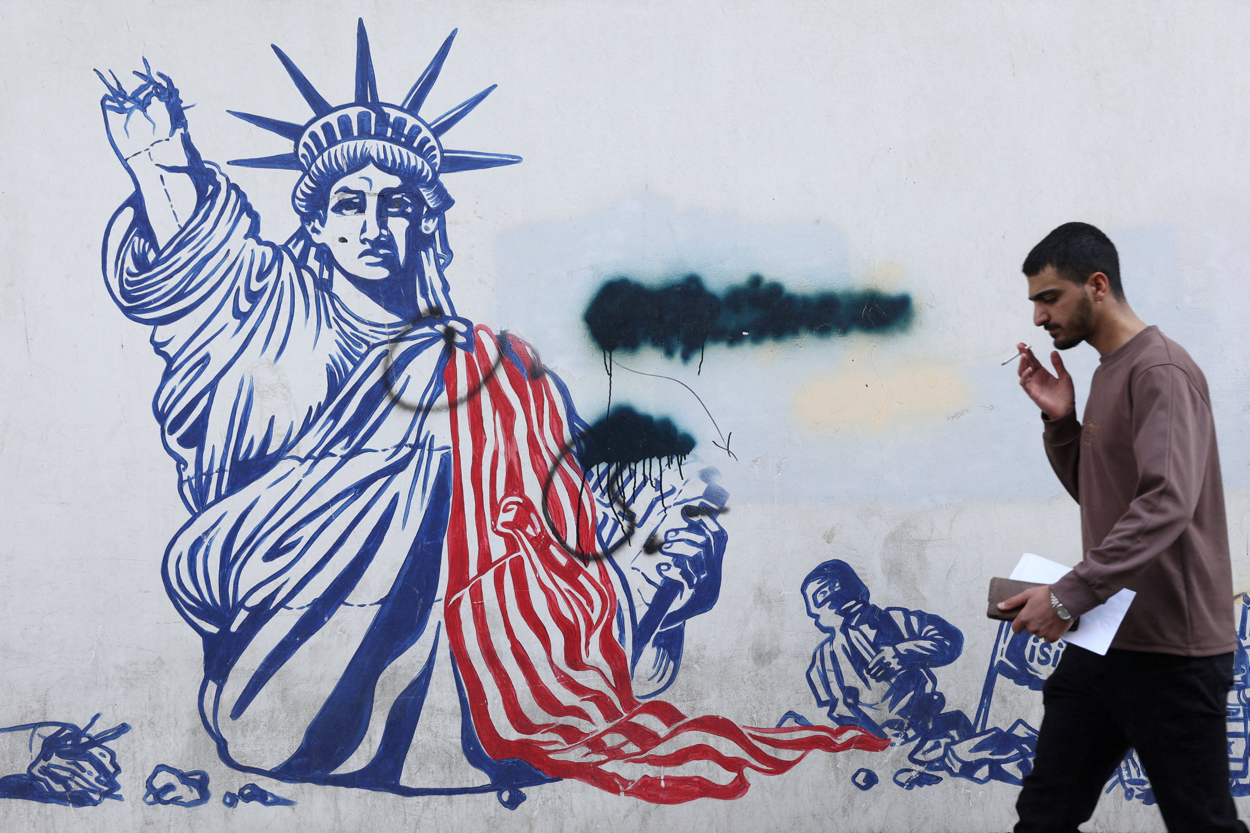 A man walks past a mural depicting a damaged Statue of Liberty in Tehran on Thursday. Photo: WANA via Reuters