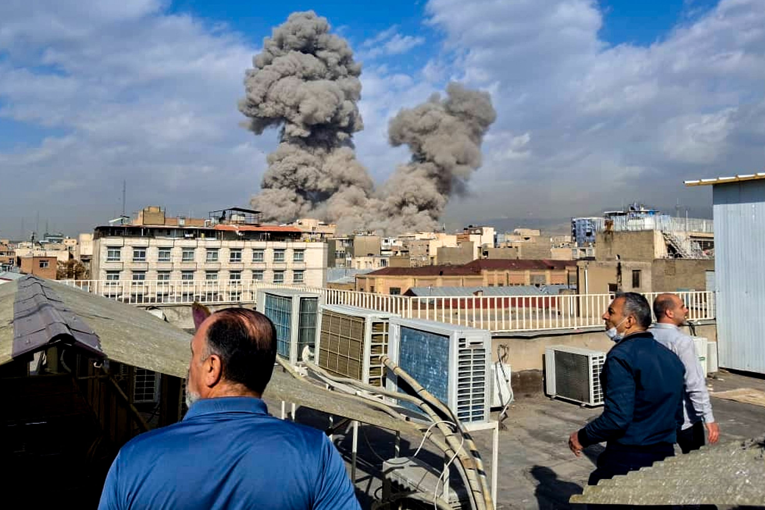 People watch as smoke rises on the skyline after an explosion in Tehran, Iran, on February 28. Photo: AP
