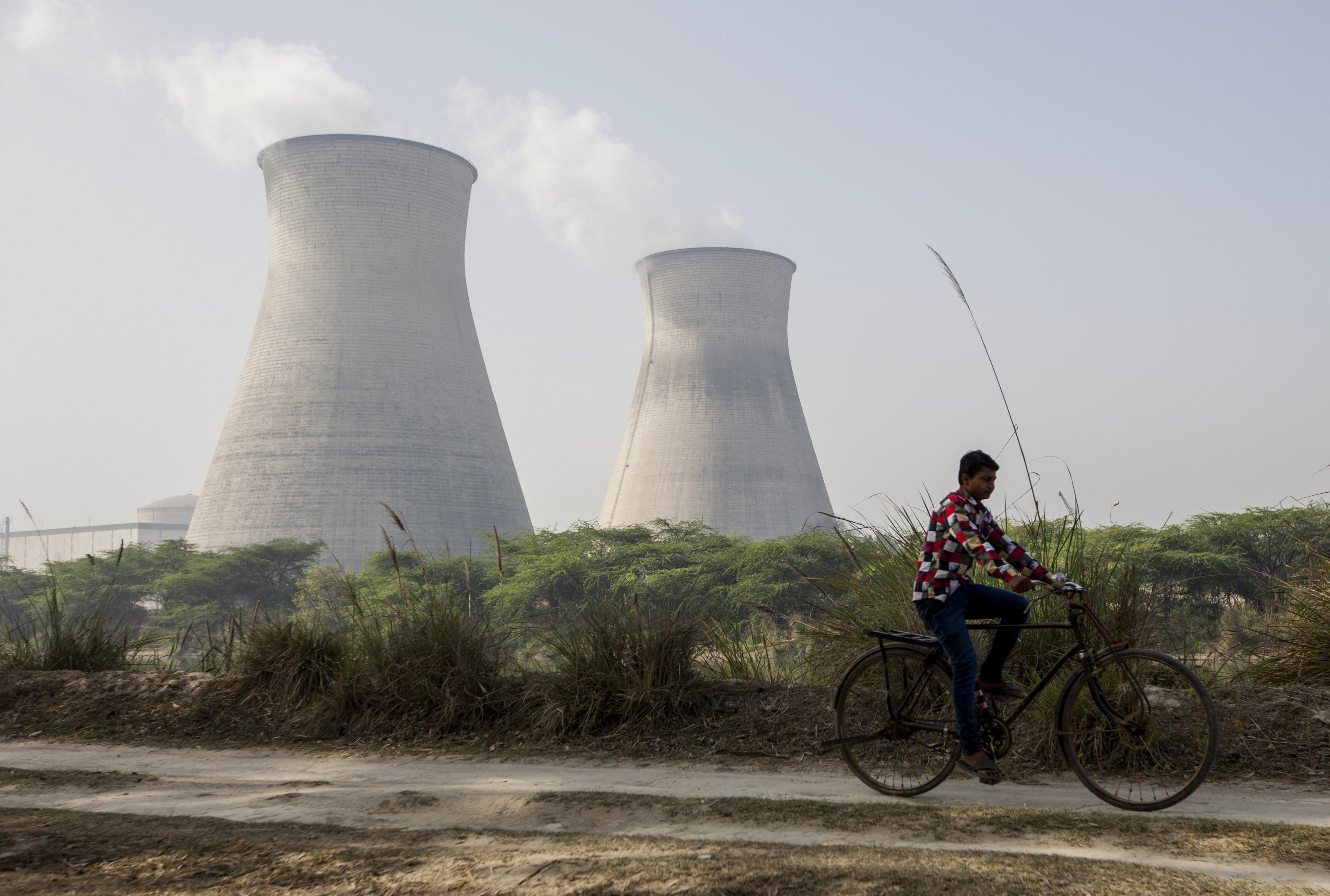 An Indian man cycles along a dirt road next to the Norora Atomic Power Station in India’s Uttar Pradesh state. Photo: AFP