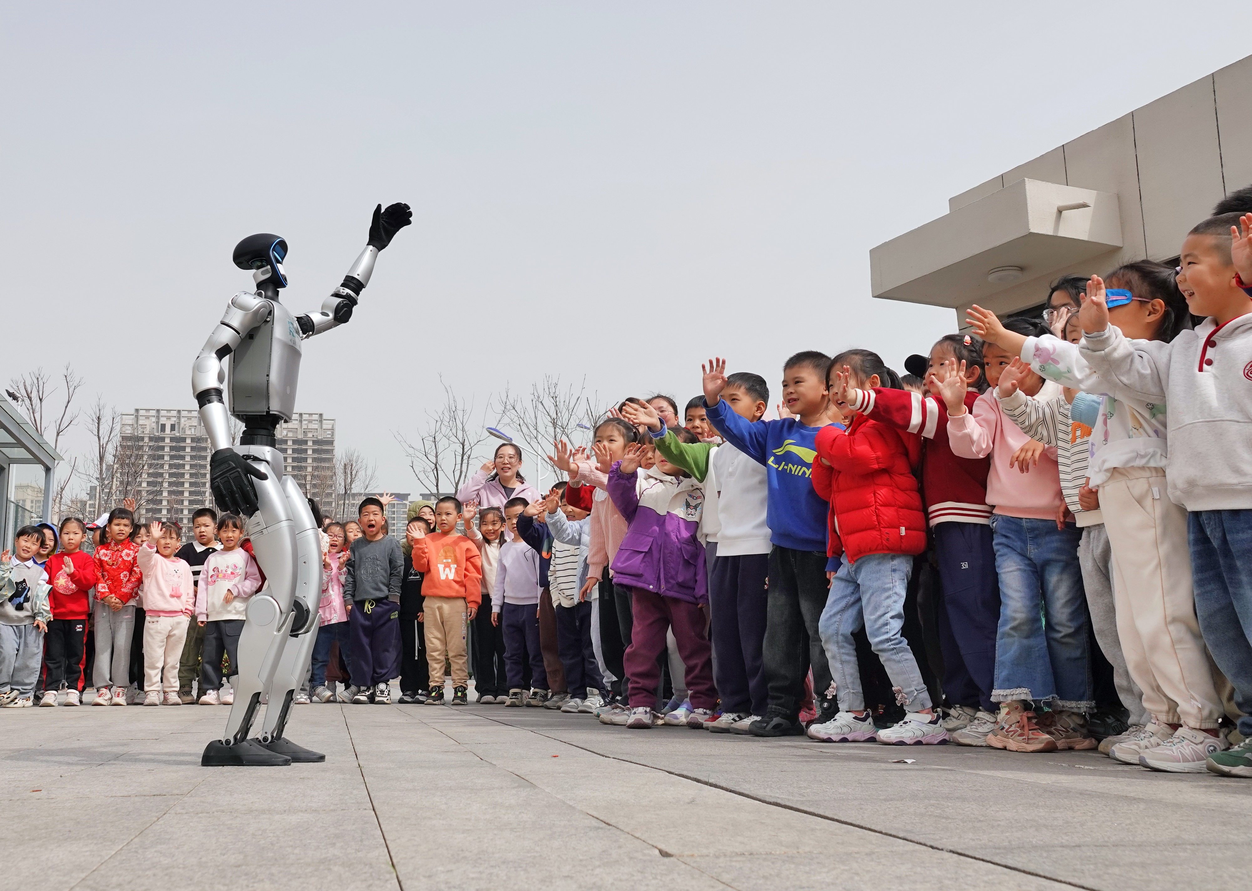 A humanoid robot waves to children at a kindergarten in China’s eastern Shandong province. Photo: Getty Images