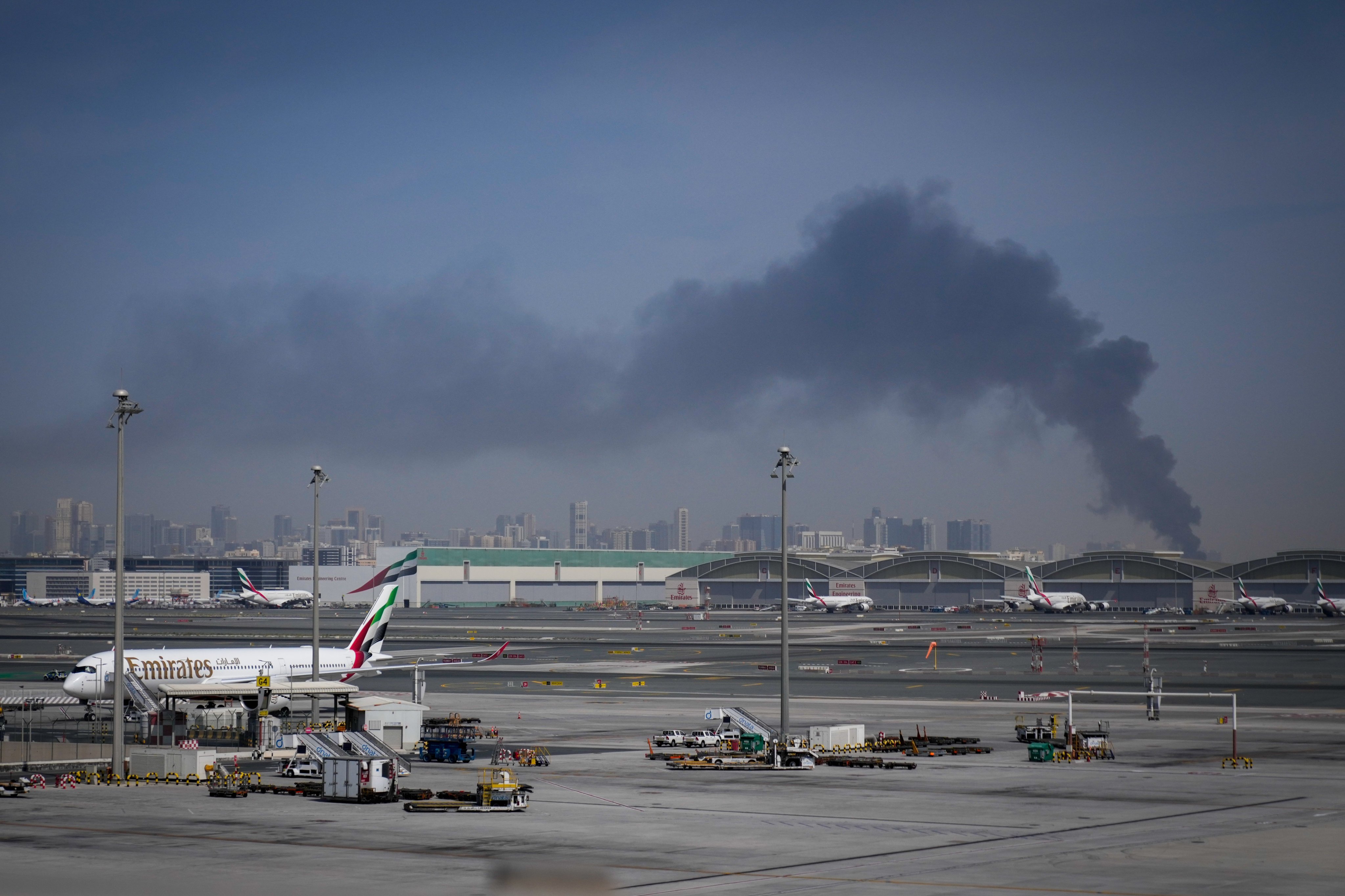 A plume of smoke from an Iranian strike rises behind planes parked at Dubai International Airport on Sunday, March 1. Photo: AP