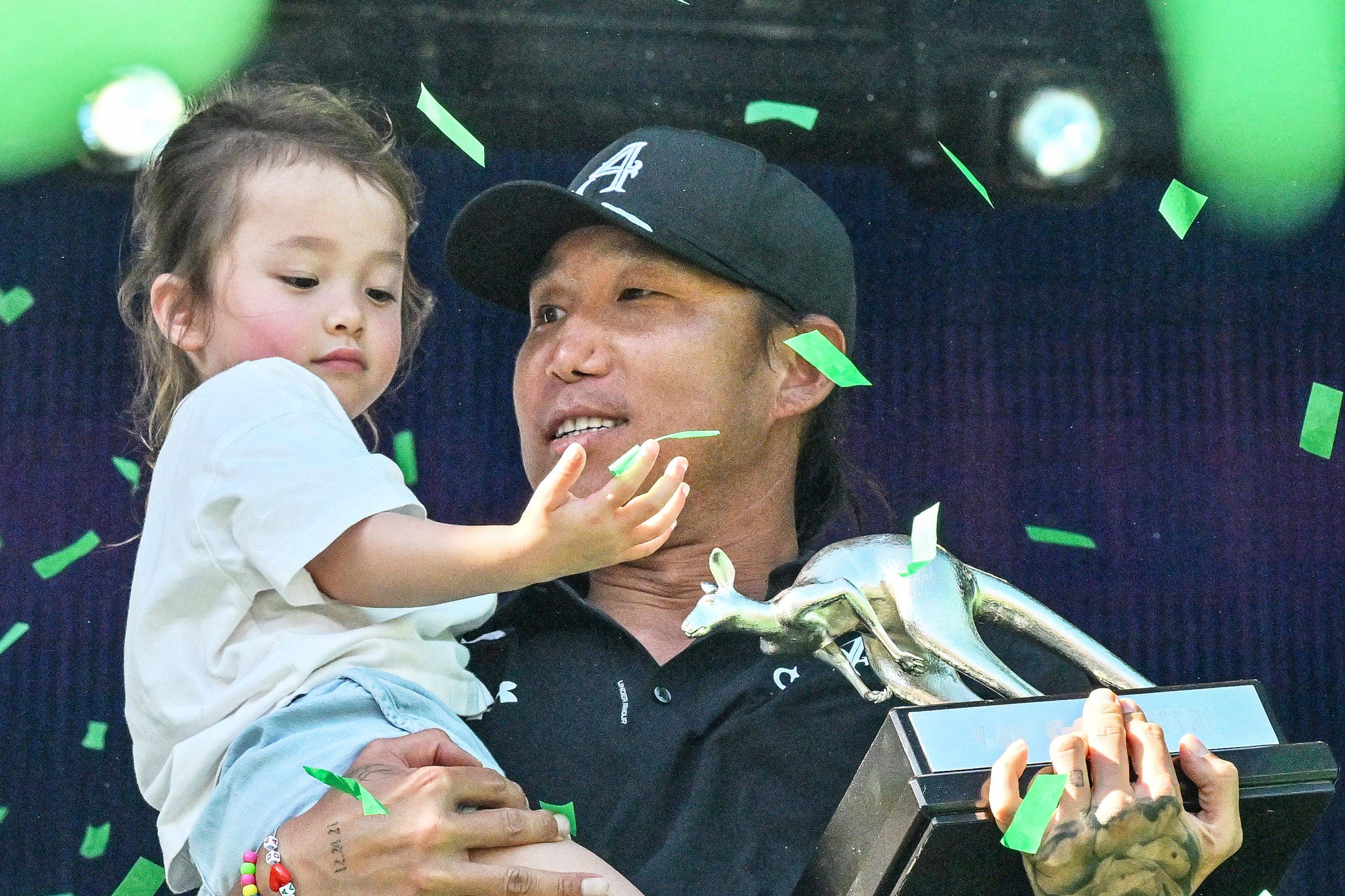 Anthony Kim celebrates on the podium with daughter Isabella after winning LIV Golf Adelaide. Photo: AFP