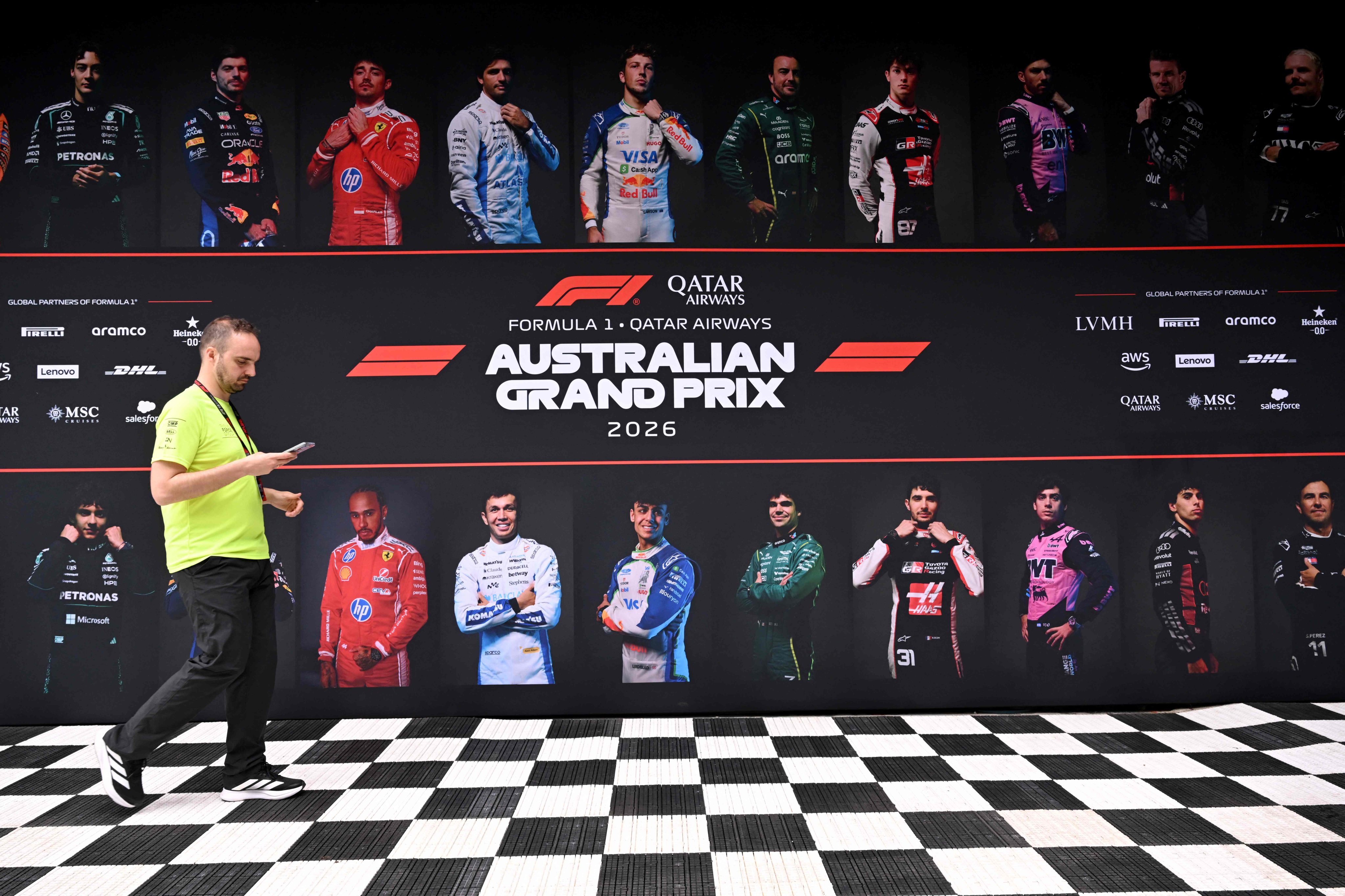 A crew member walks past images of drivers as teams prepare for Sunday’s Australian Grand Prix at the Albert Park Circuit in Melbourne. Photo: AFP