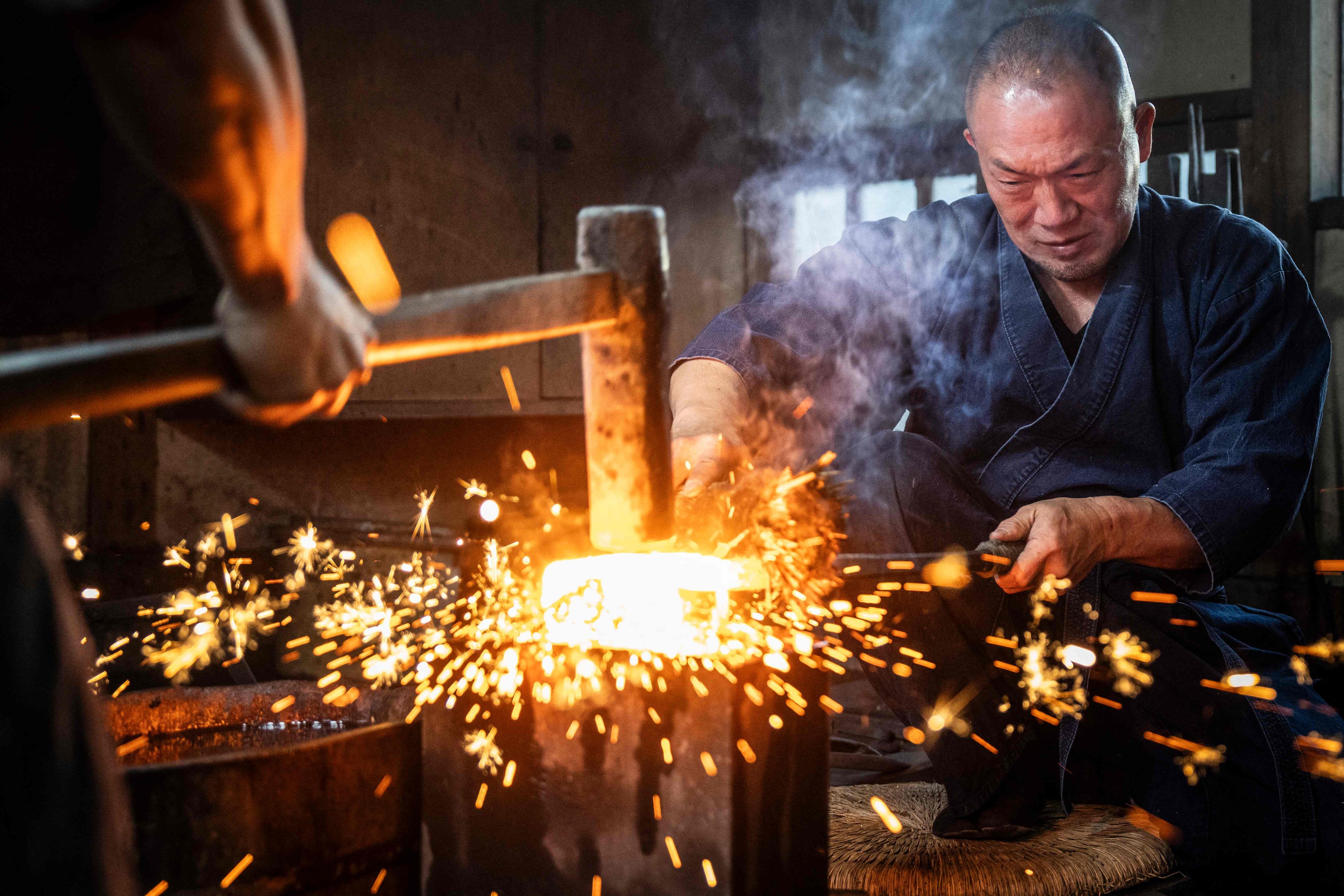Sparks fly as swordsmith Akihira Kawasaki steadies steel over an anvil while his apprentice hammers the metal to forge katana blades at Kawasaki’s workshop in Misato, Saitama prefecture, Japan. Photo: AFP
