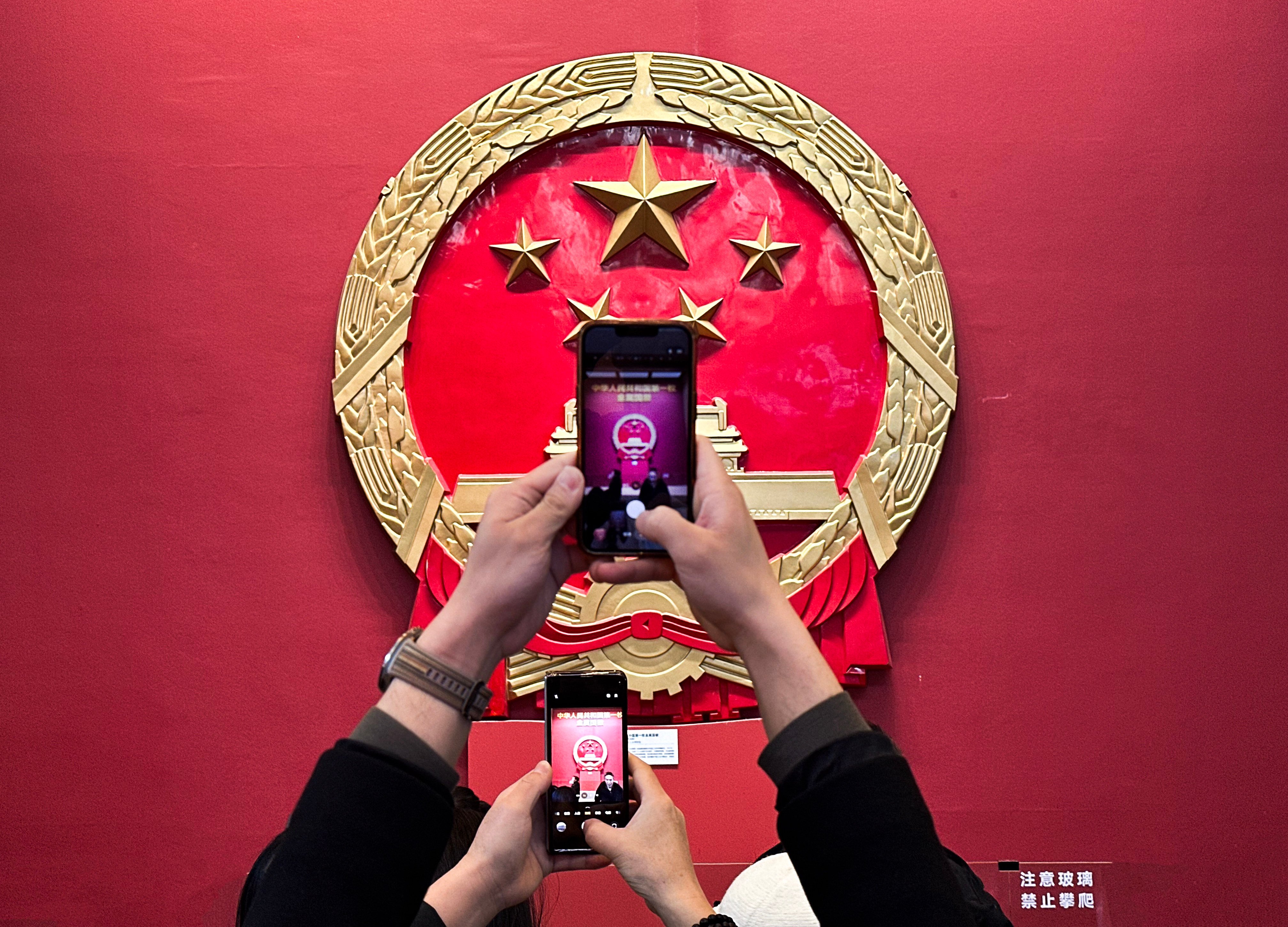 Visitors take photos of the life-size replica of China’s first metal national emblem at the National Museum of China in Beijing on March 3. Photo: Robert Ng