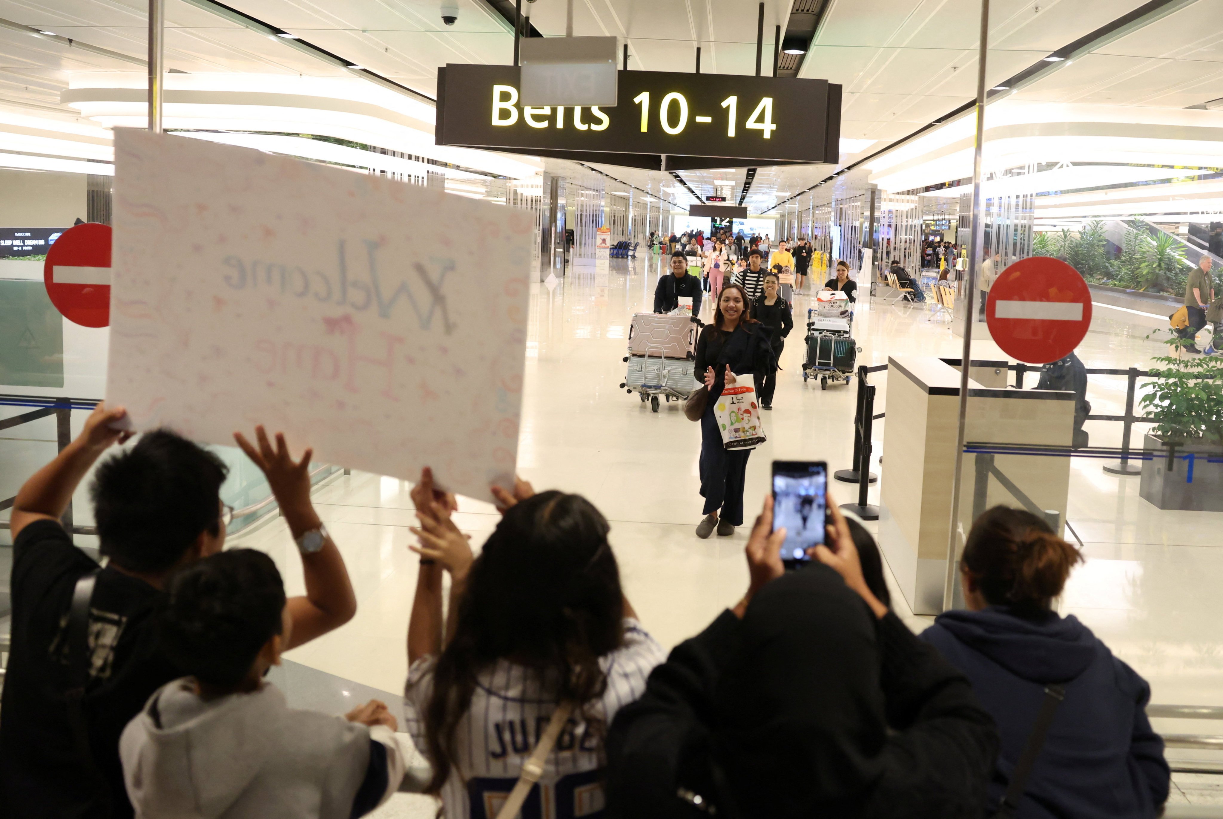 Family members cheer as passengers return to  Singapore from the Middle East at Changi Airport on Thursday. Photo: Reuters