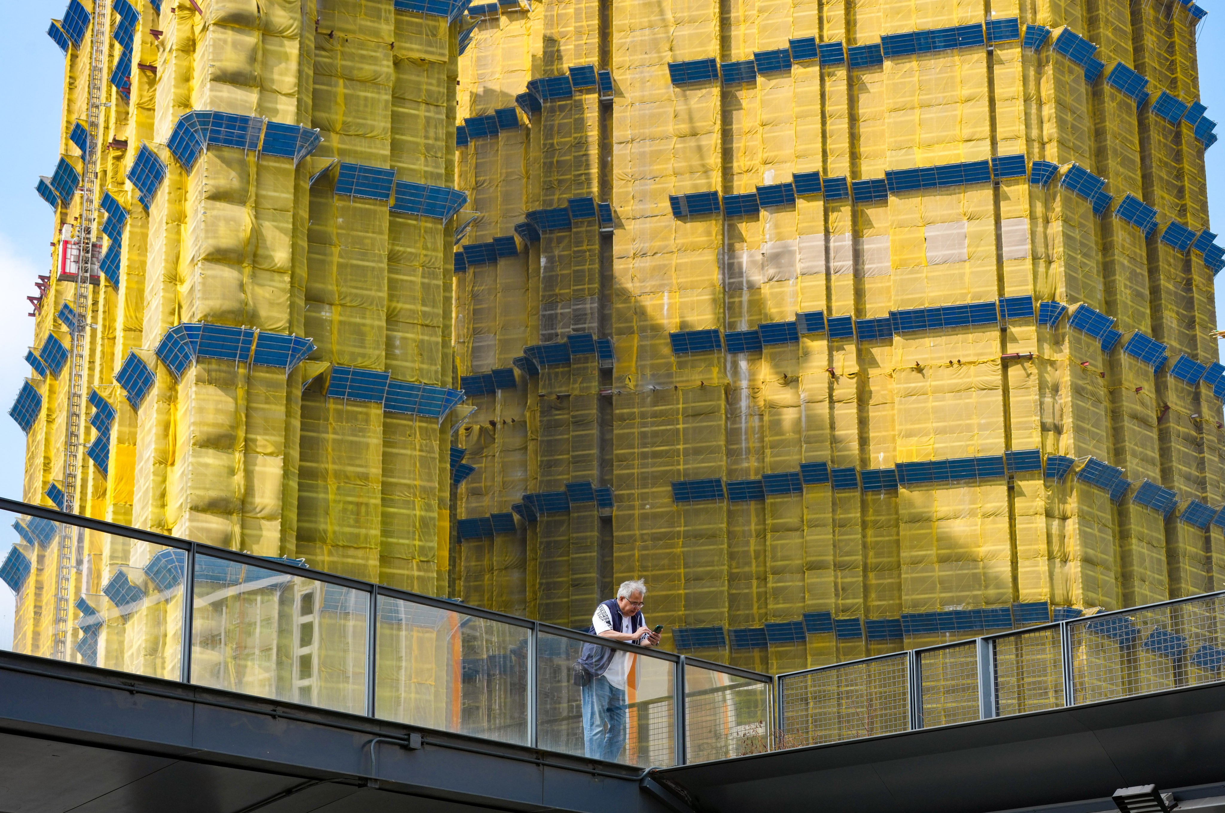 A man looks at his mobile phone in Kai Tak in front of a residential building under construction. Photo: Jelly Tse