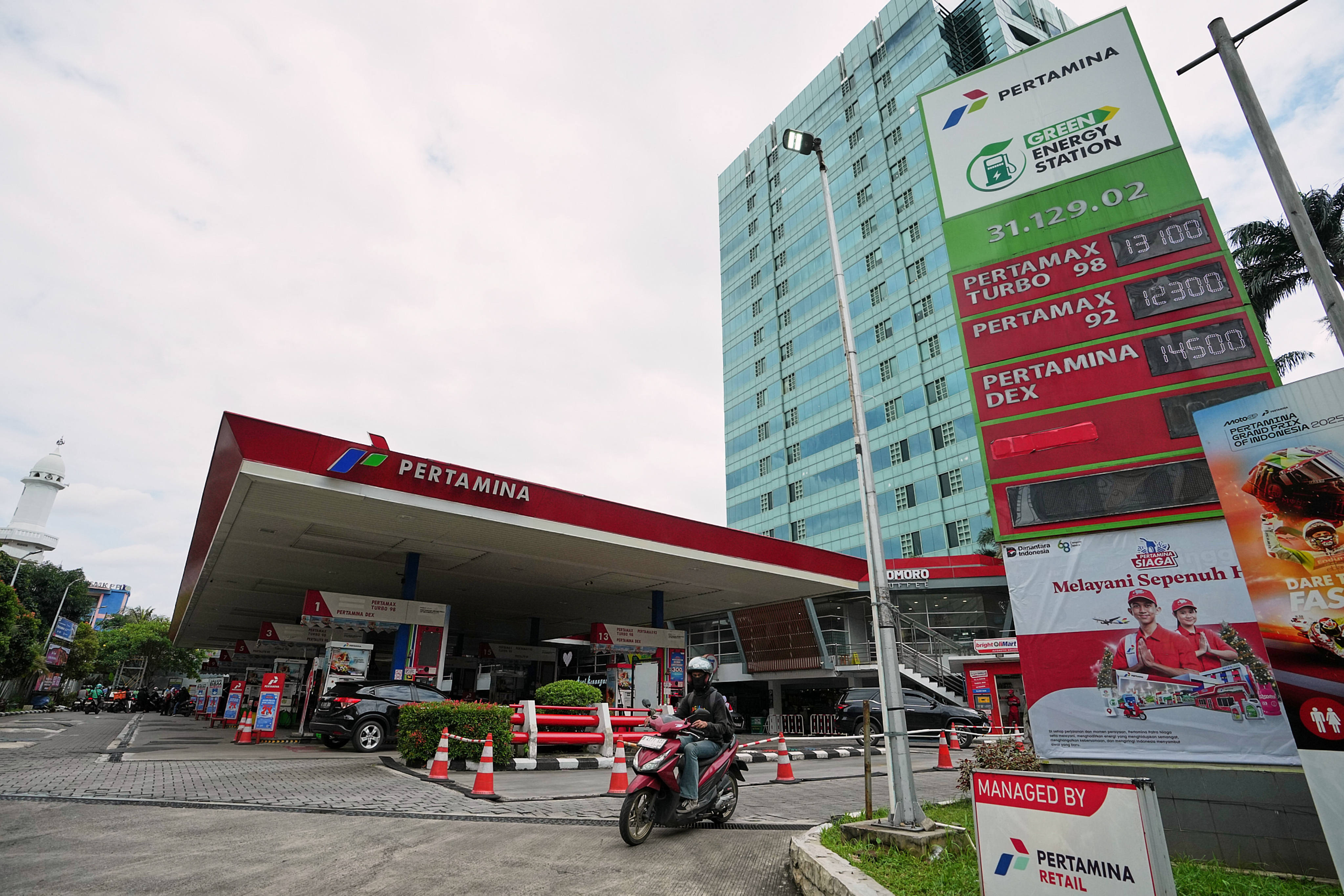 A motorist rides past a Pertamina petrol station displaying prices of fuel in  Jakarta on Tuesday. Photo: AP