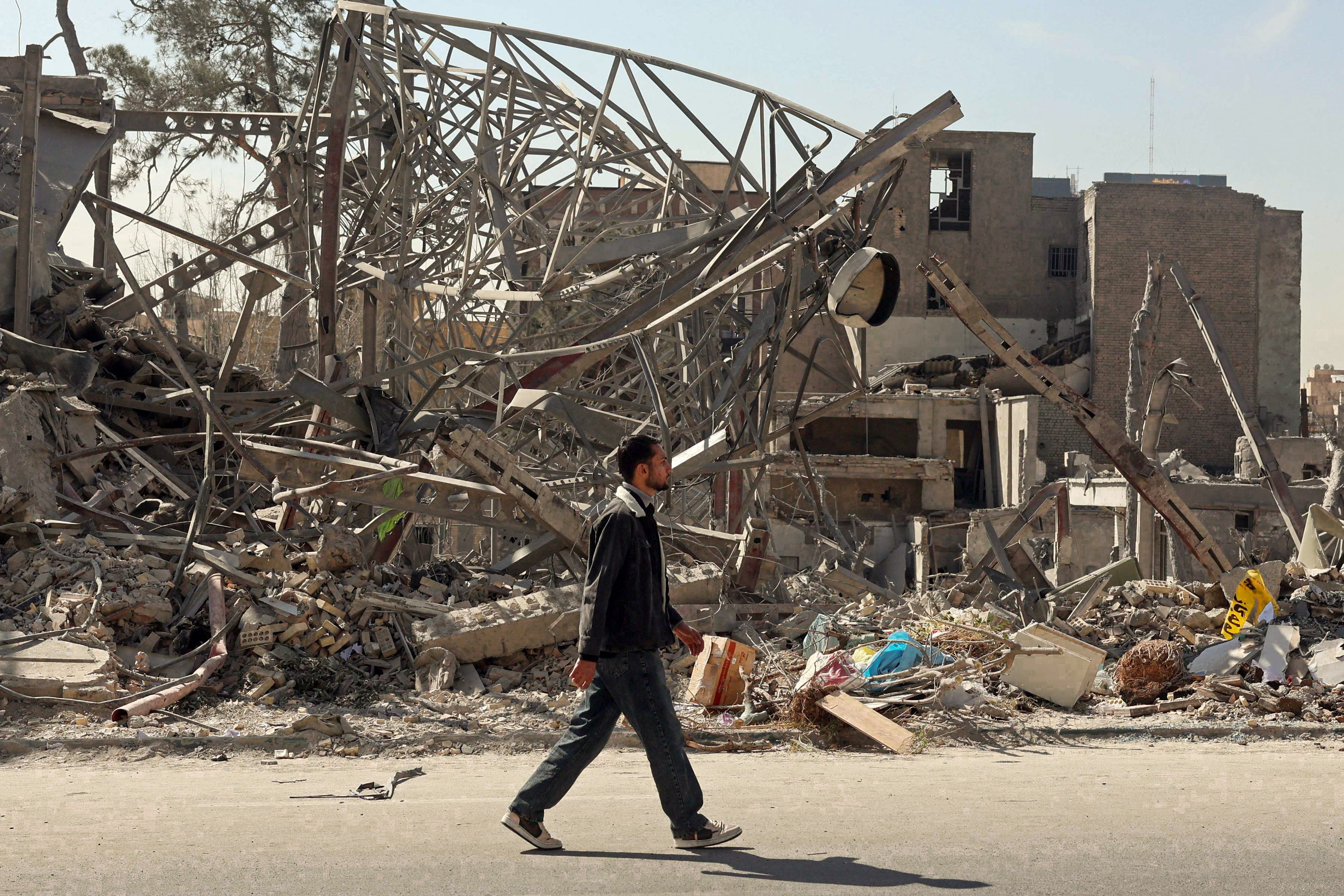 A man in Tehran walks past the aftermath of airstrikes on the city. Photo: AFP
