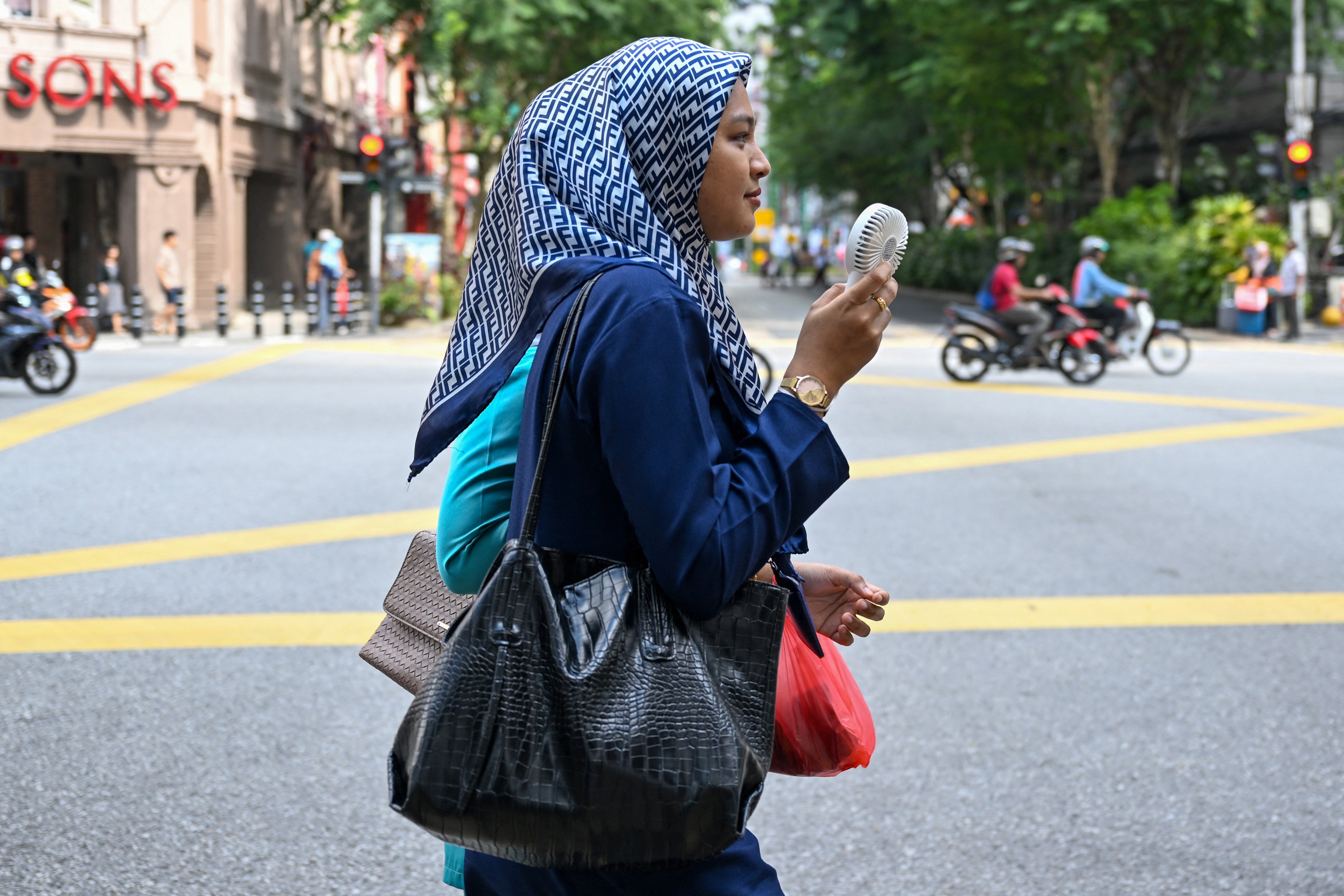 A women uses an electric fan to cool off in Kuala Lumpur, Malaysia. Photo: AFP