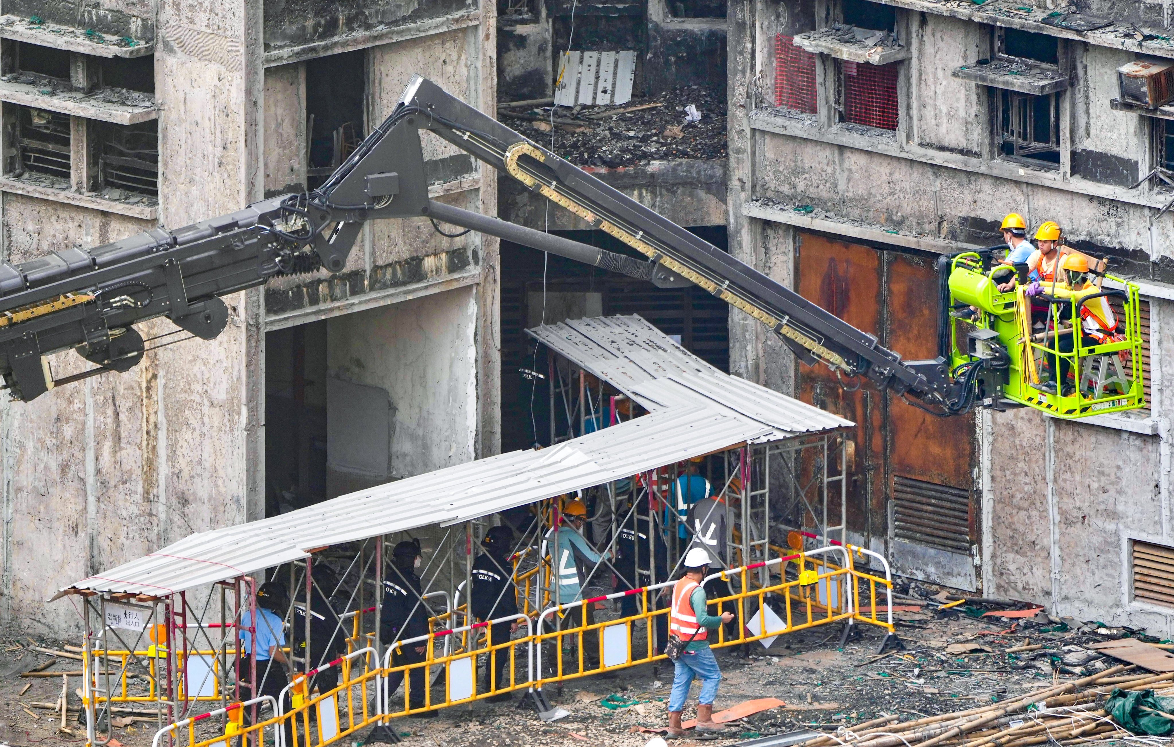 Construction workers at Wang Fuk Court are escorted by police officers as part of enhanced security screening. Photo: Sam Tsang