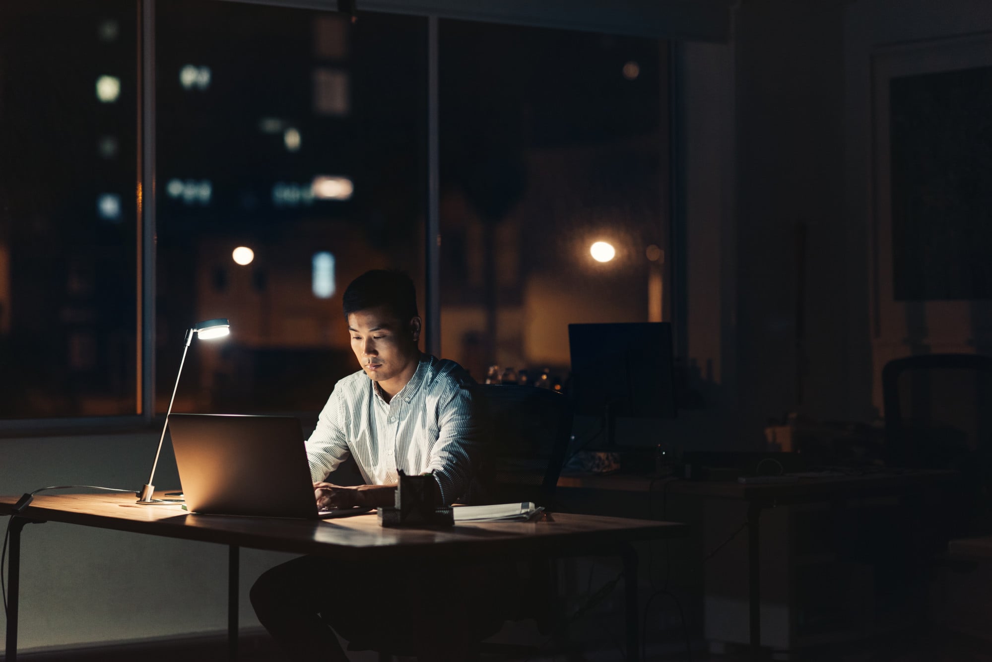 Pressure of work: A young Asian businessman burns the midnight oil at the office. Photo: Shutterstock