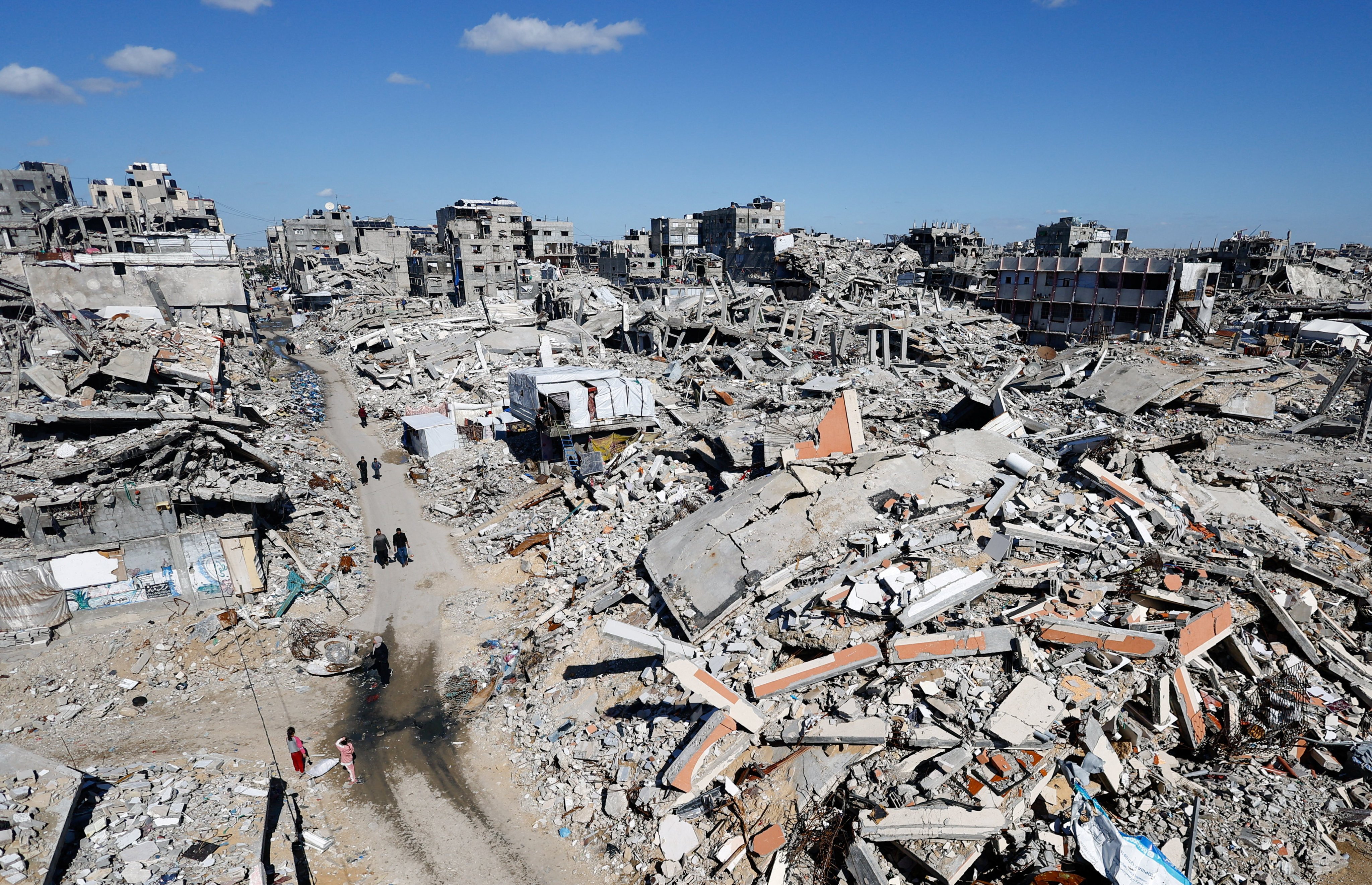 Palestinians walk past the rubble of residential buildings destroyed during the two-year Israeli offensive, in Jabalia, northern Gaza Strip. Photo: Reuters
