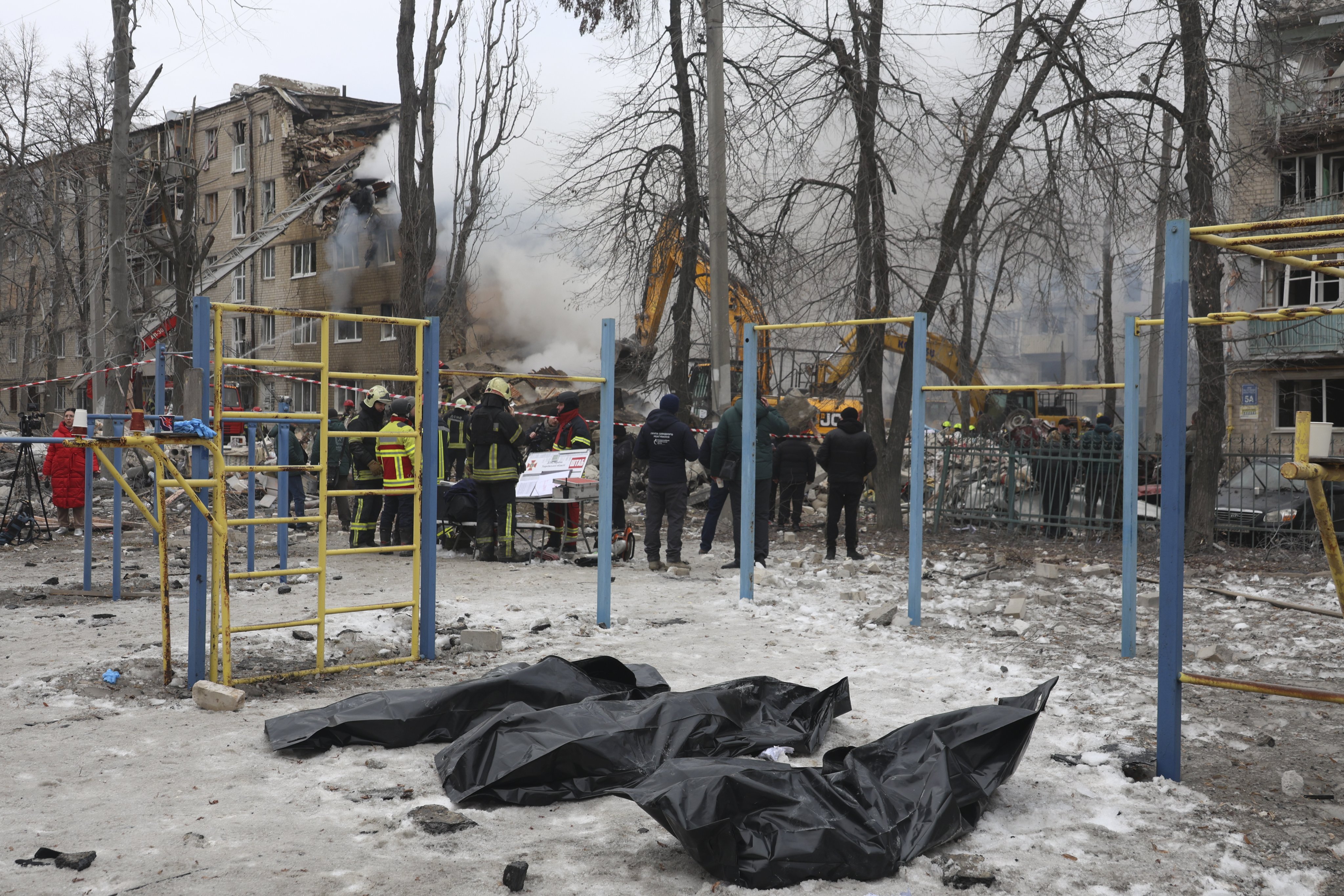Rescuers stand near bodies retrieved from the site of a strike on a residential building in Kharkiv, northeastern Ukraine, on Saturday. Photo: EPA