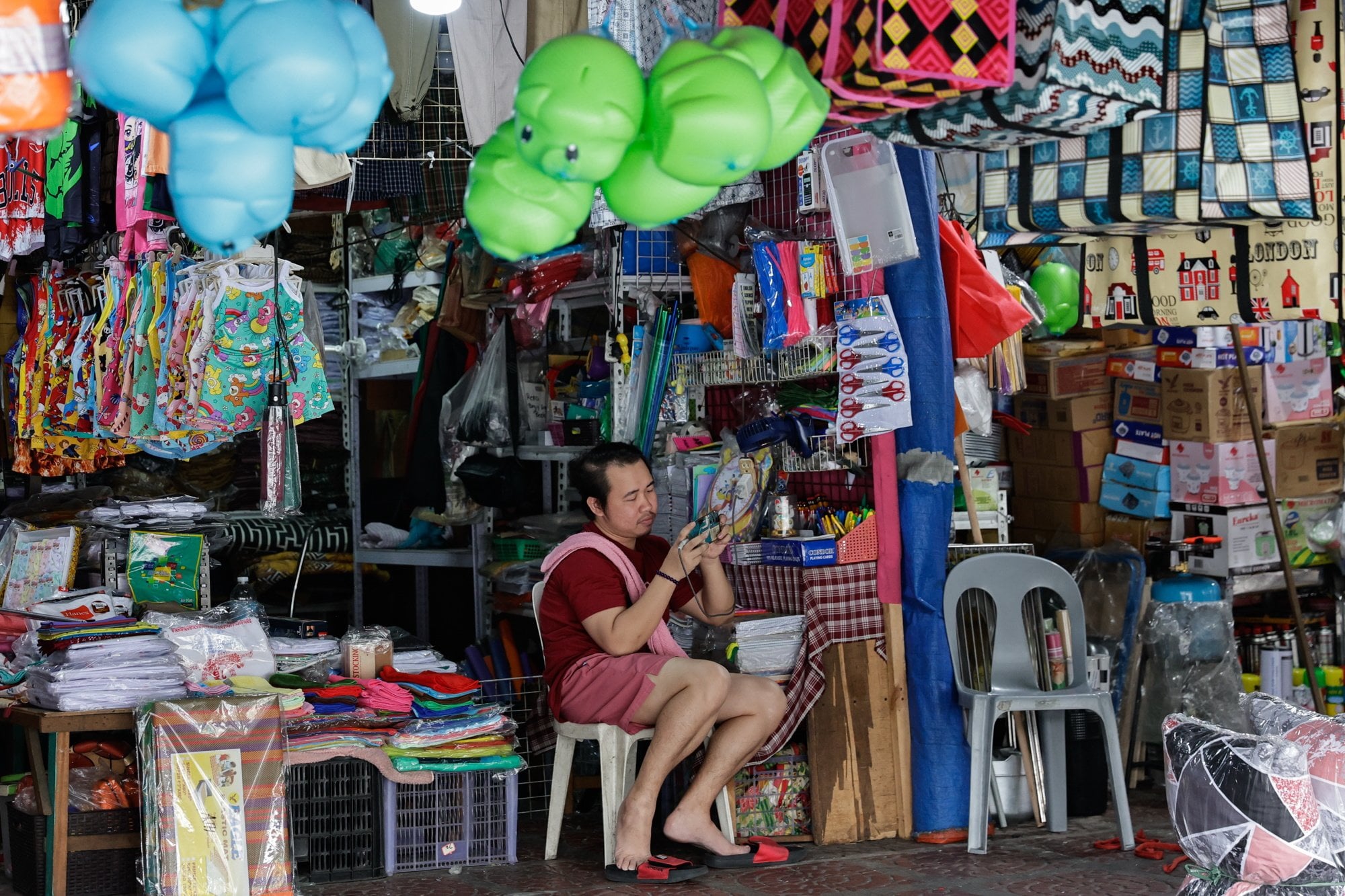 A shopkeeper looks at his smartphone while waiting customers in Manila. The Philippines’ budget deficit hit a record high last year. Photo: EPA
