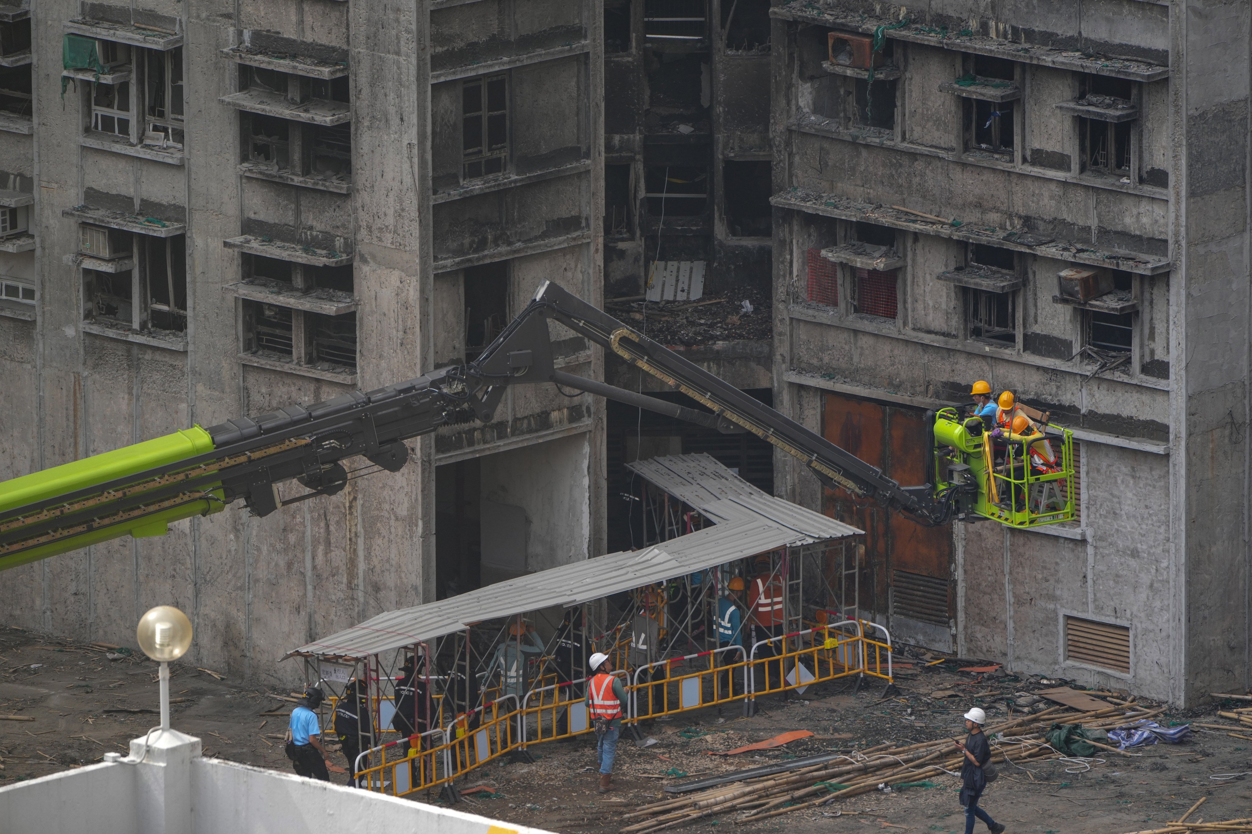 Construction workers enter one of the buildings of Wang Fuk Court in Tai Po, along with police officers, for structural reinforcement work on March 9. Photo: Sam Tsang