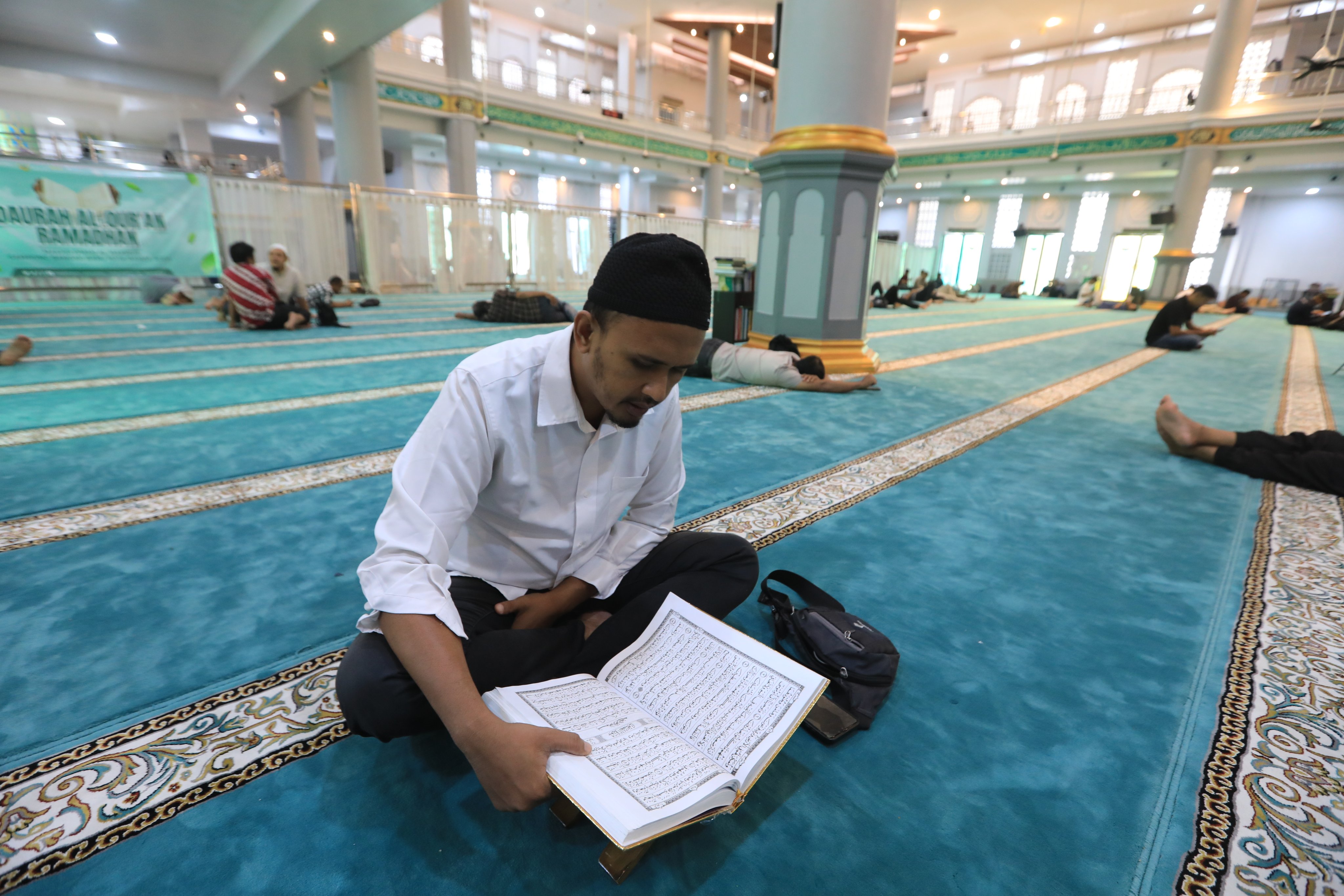 A Muslim man reads the Quran while waiting to break fast during the holy month of Ramadan in Banda Aceh, Indonesia, on Thursday. Photo: EPA
