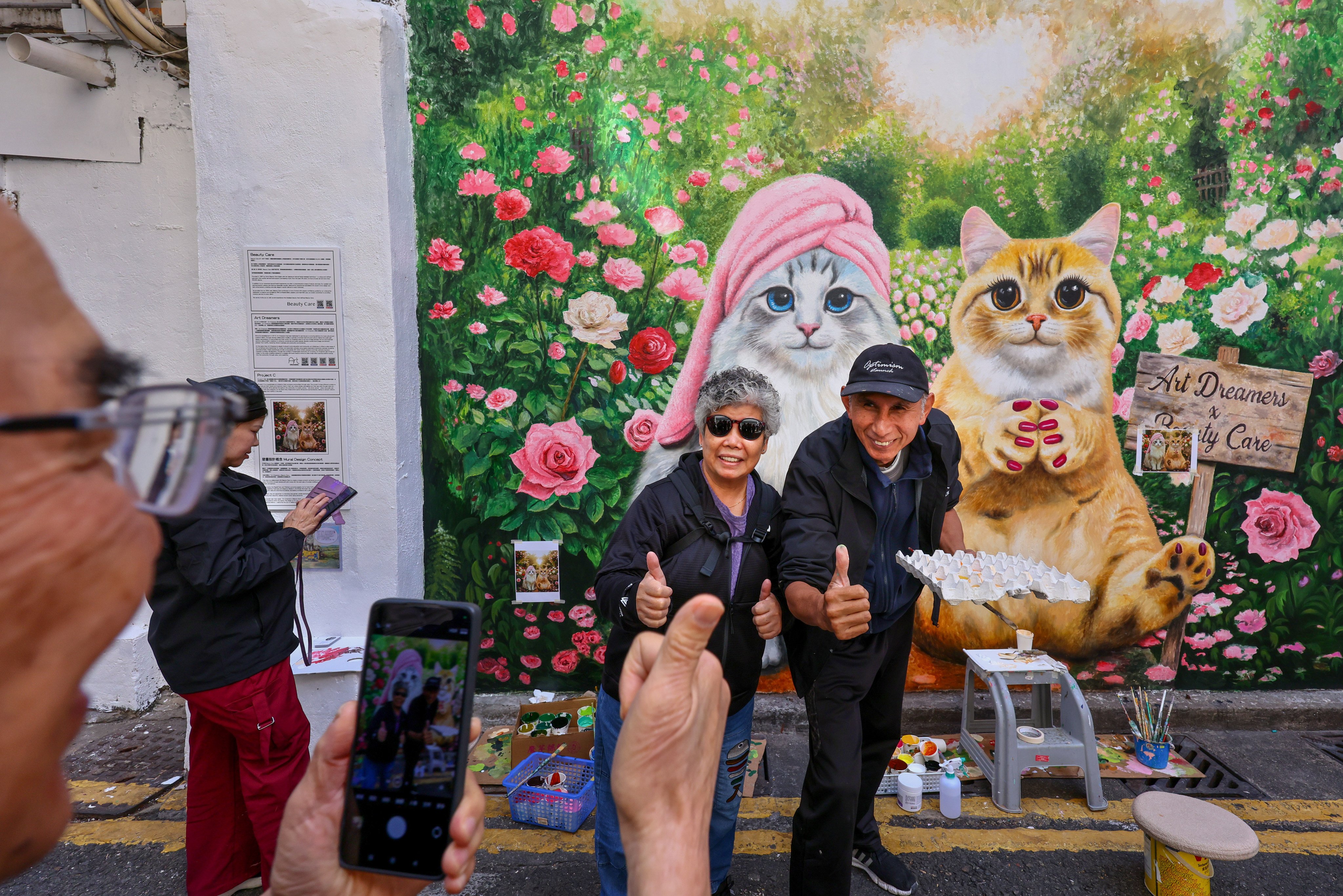 Artist Li Hok-fung (right) takes a photo with a resident in front of his popular cat-themed mural at Kiu Kong Mansion in Yau Ma Tei. Photo: Dickson Lee