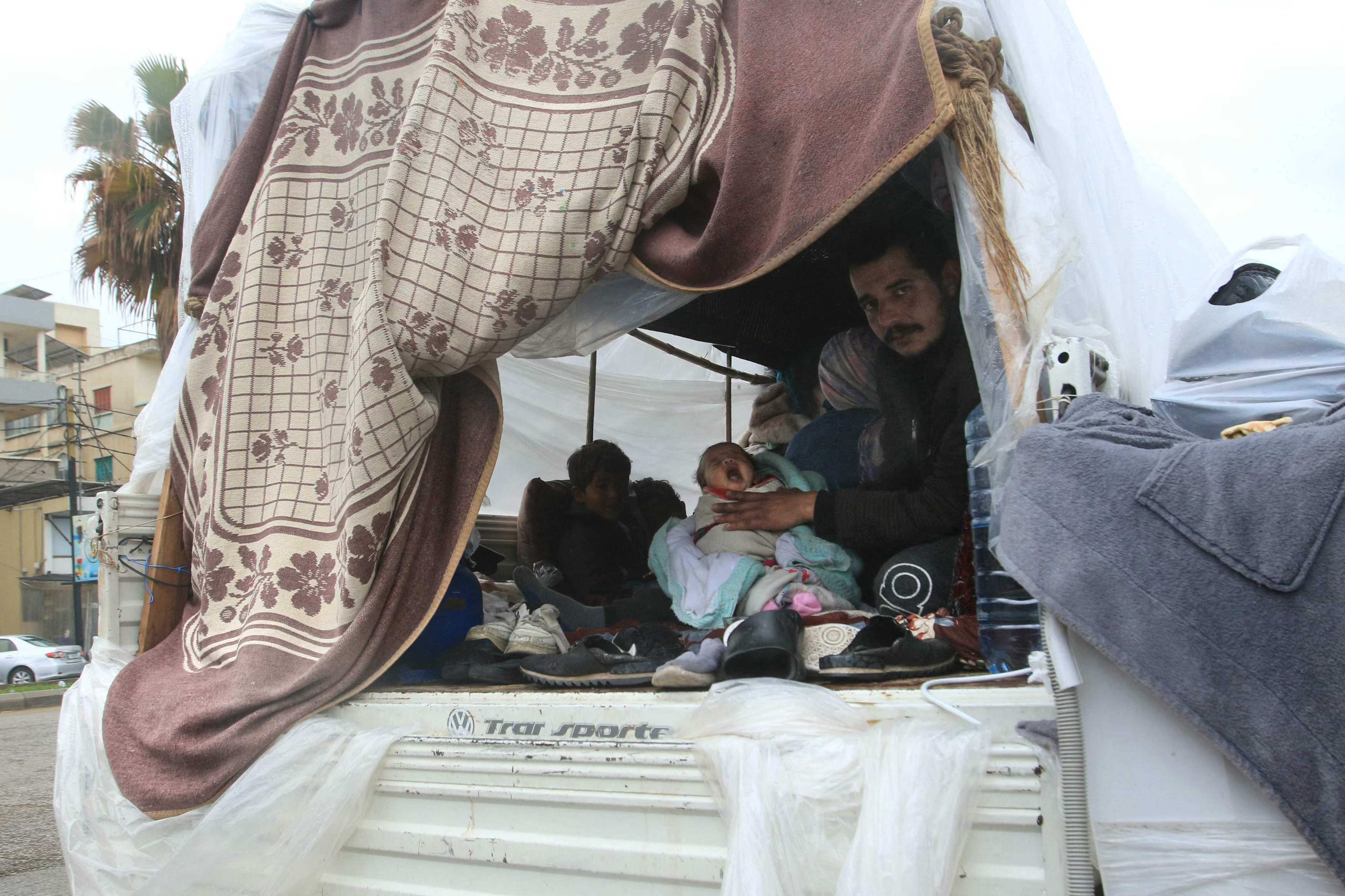 A displaced Lebanese family sit in the back of a truck, their current home, in the southern city of Sidon on Sunday. Photo: AFP