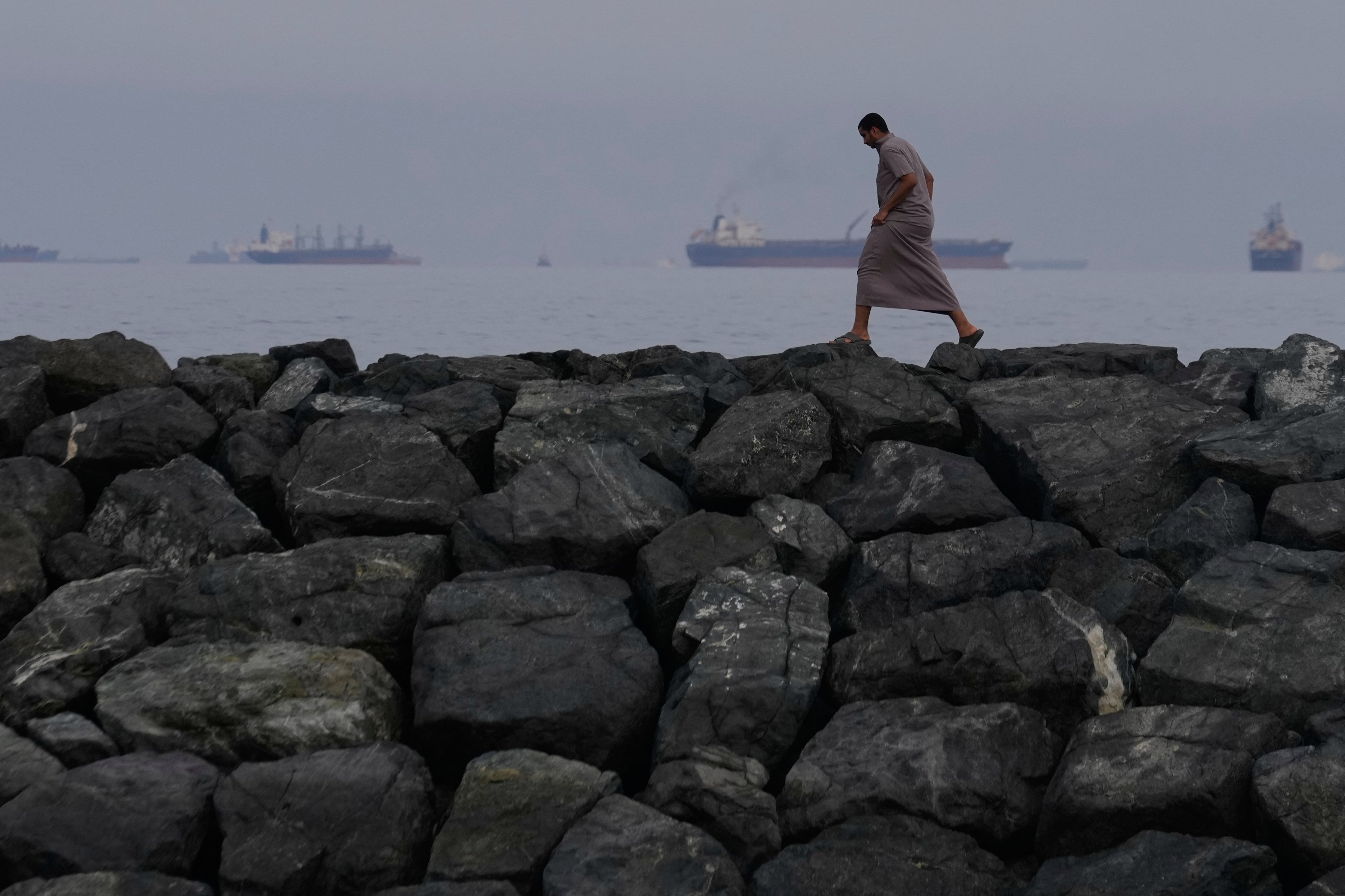 A man walks along the shore as oil tankers and cargo ships line up in the Strait of Hormuz, as seen from Khor Fakkan, the United Arab Emirates, on March 11, 2026. Photo: AP