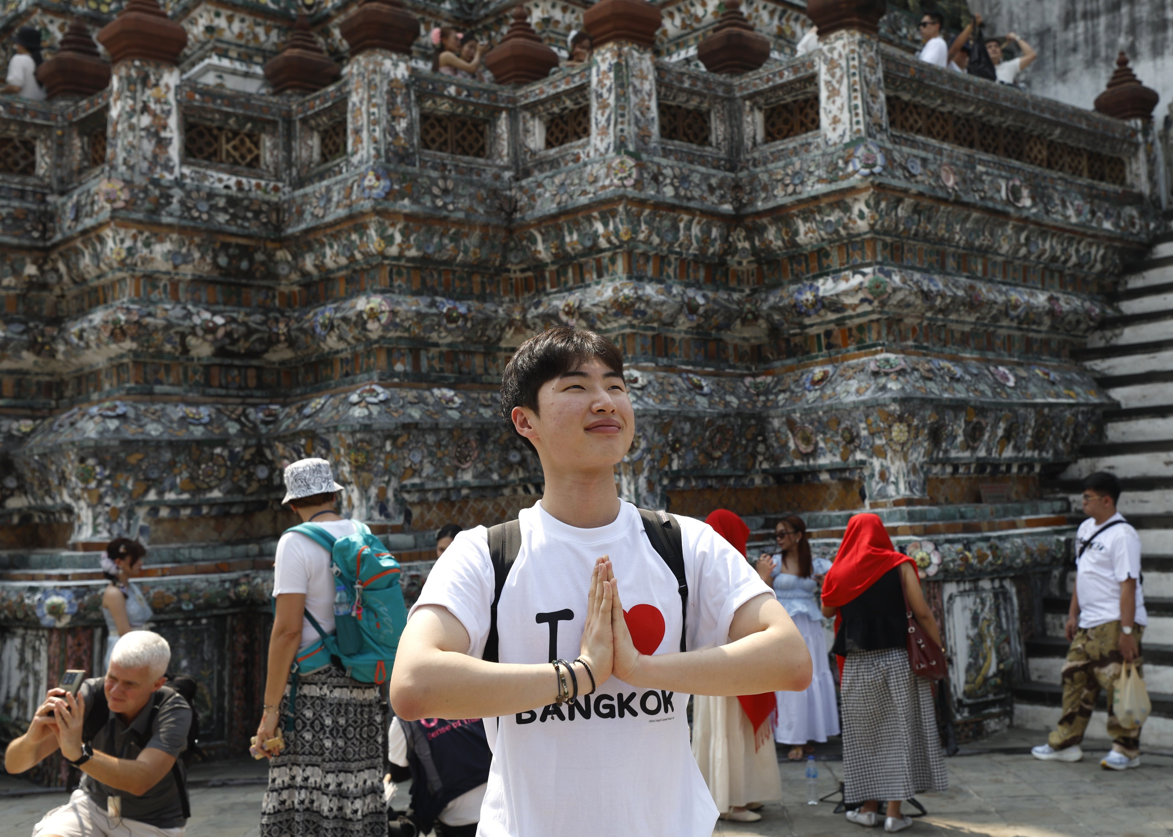A tourist poses for a photo doing the traditional Thai greeting during his visit to the Temple of Dawn in Bangkok on January 19. Photo: EPA