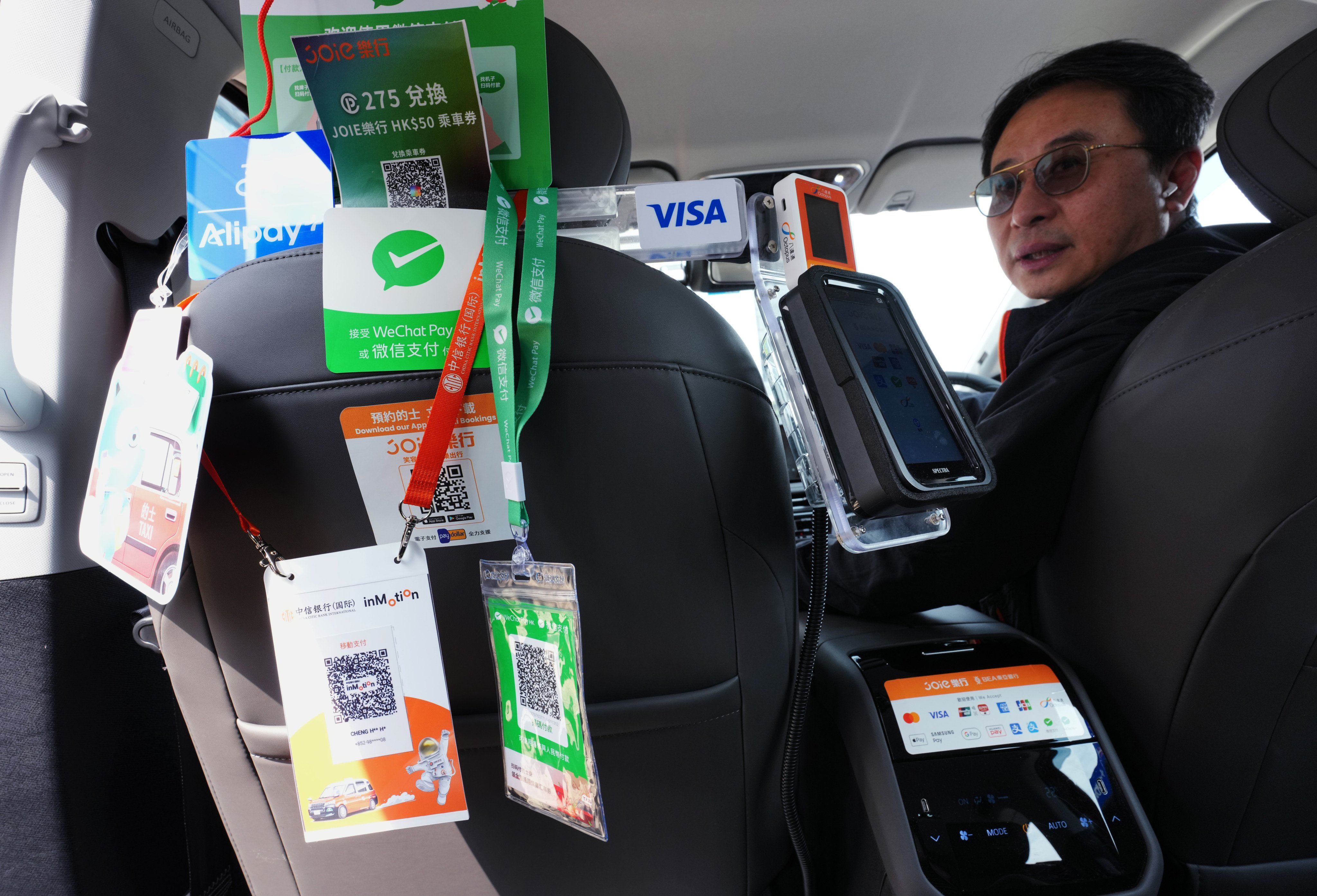 A taxi interior is plastered with advertising for various electronic payment systems for settling fares, on March 10. Taxis are required to offer at least two e-payment options – one QR code-based and one non-QR code method – from April 1. Photo: Jelly Tse