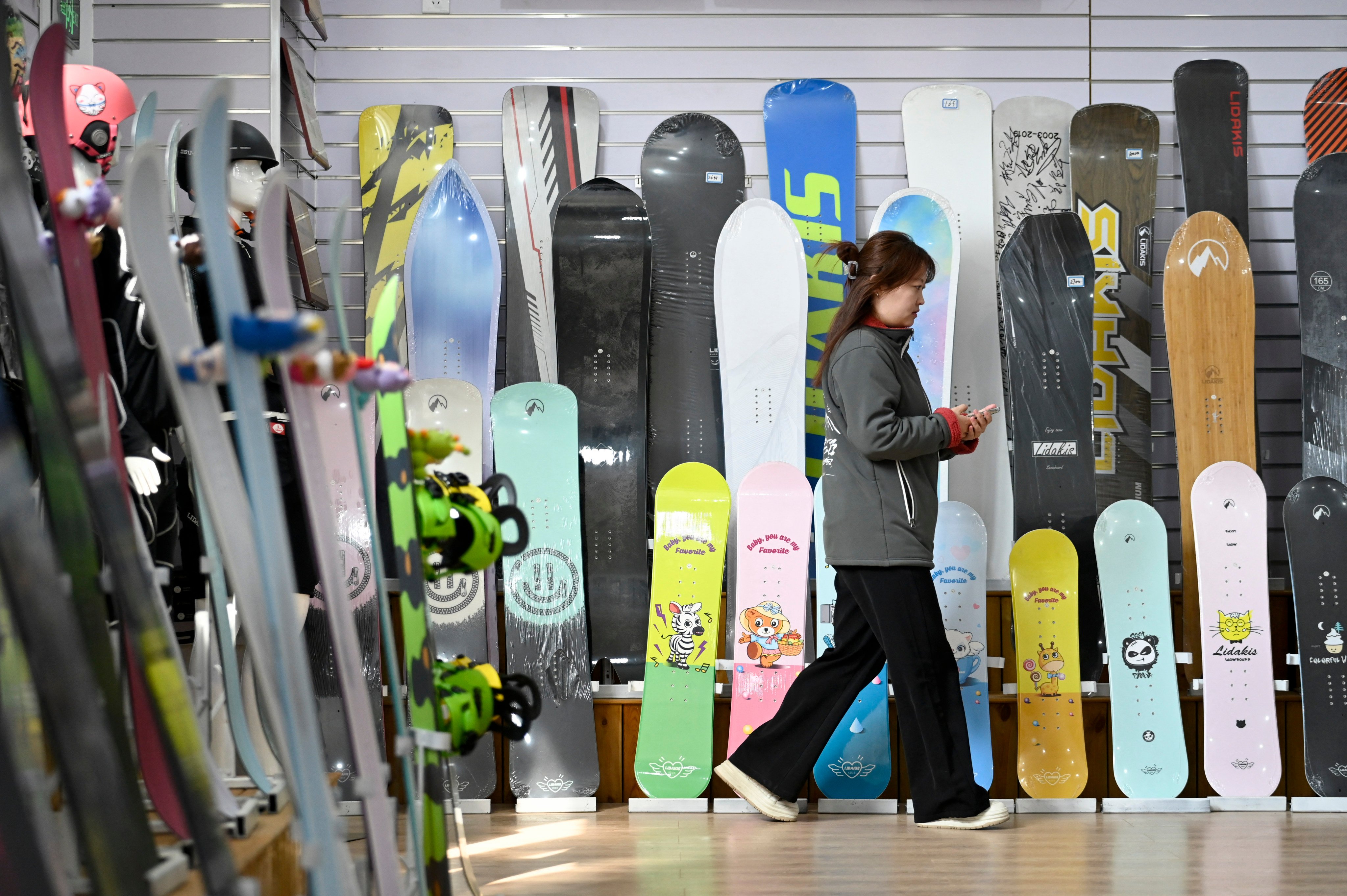 This picture taken on March 12, 2026 shows an employee walking past snowboards at a Lidakis’s exhibition room in Zhangjiakou, in China’s northern Hebei province. China’s snow-related equipment sales have surged almost fourfold since 2015, but interest has levelled off since the Beijing Winter Olympic Games in 2022 and a post-Covid boom. (Photo by WANG Zhao / AFP) / TO GO WITH AFP STORY: China-ski-olympics-leisure, FOCUS by Sam DAVIES