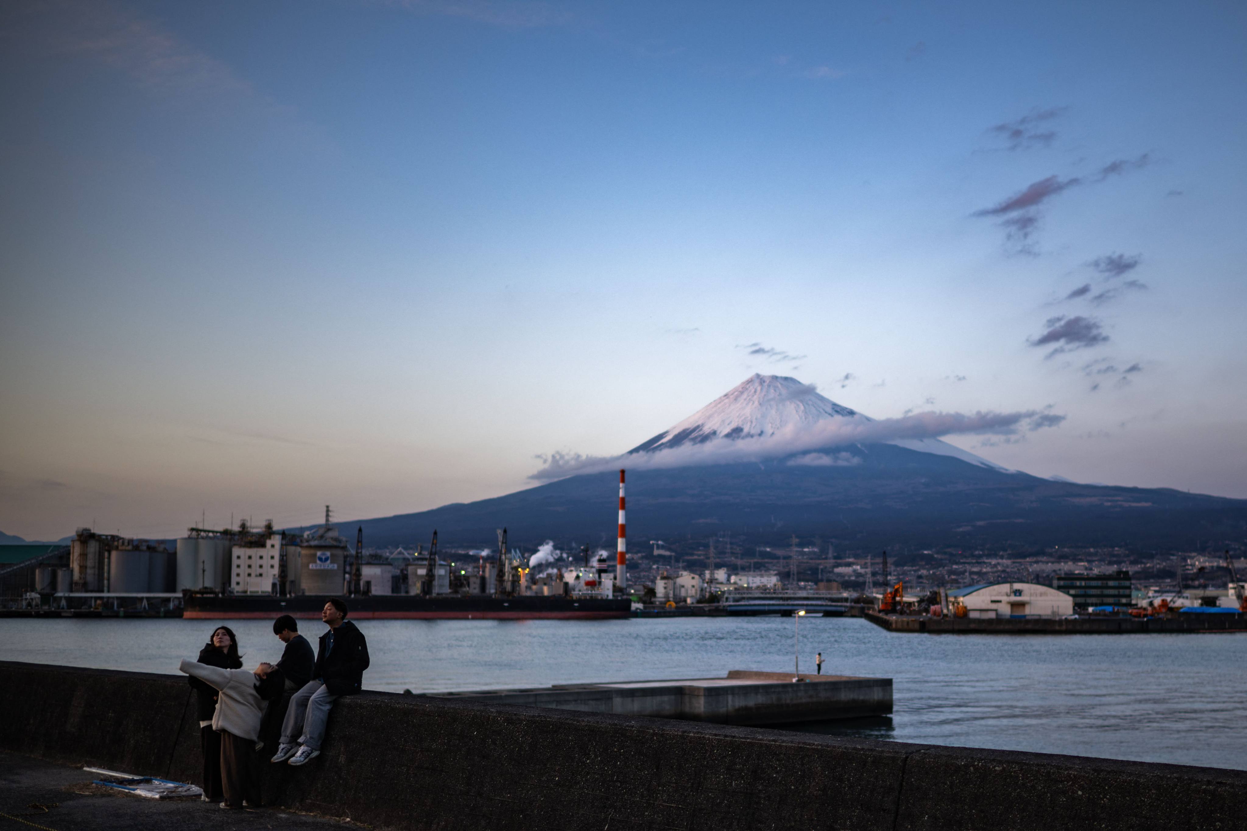 People gather at a port in Shizuoka prefecture, Japan, with Mount Fuji in the background. Photo: AFP