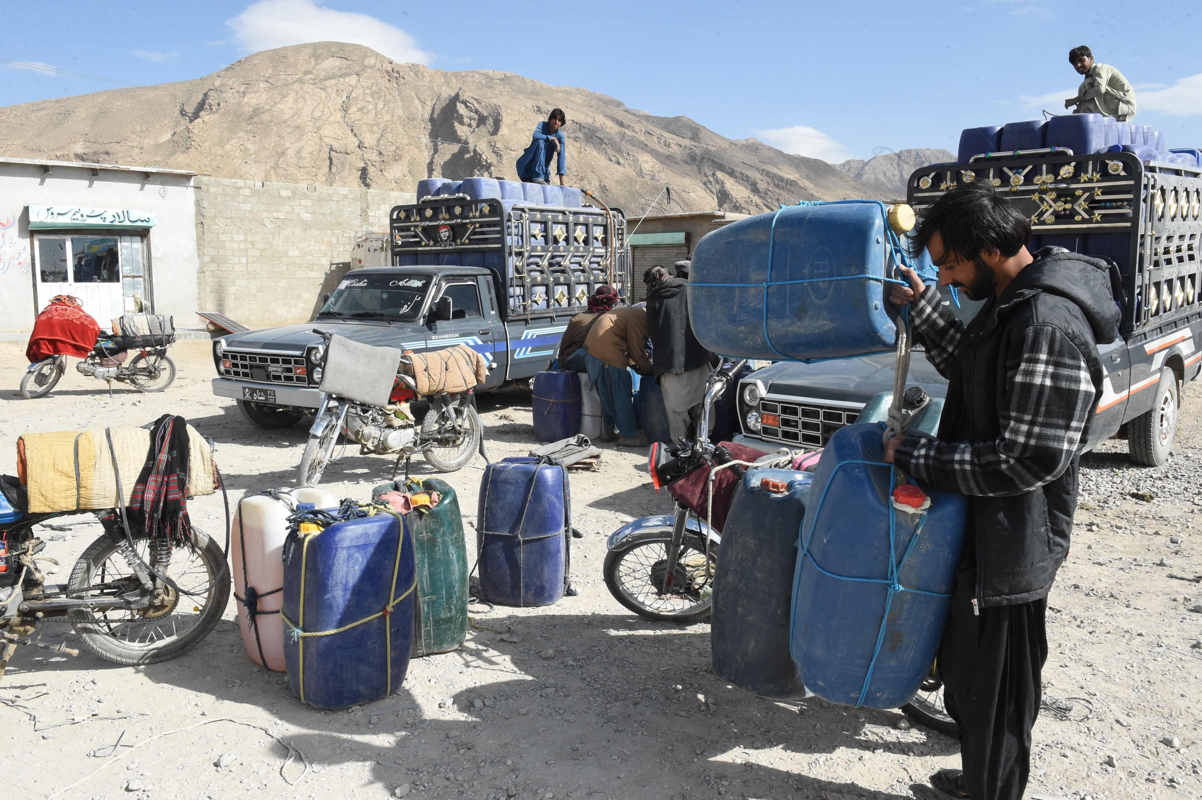 Vendors fill their jerrycans with smuggled Iranian petrol, on the outskirts of Quetta in Balochistan province on Saturday. Photo: AFP