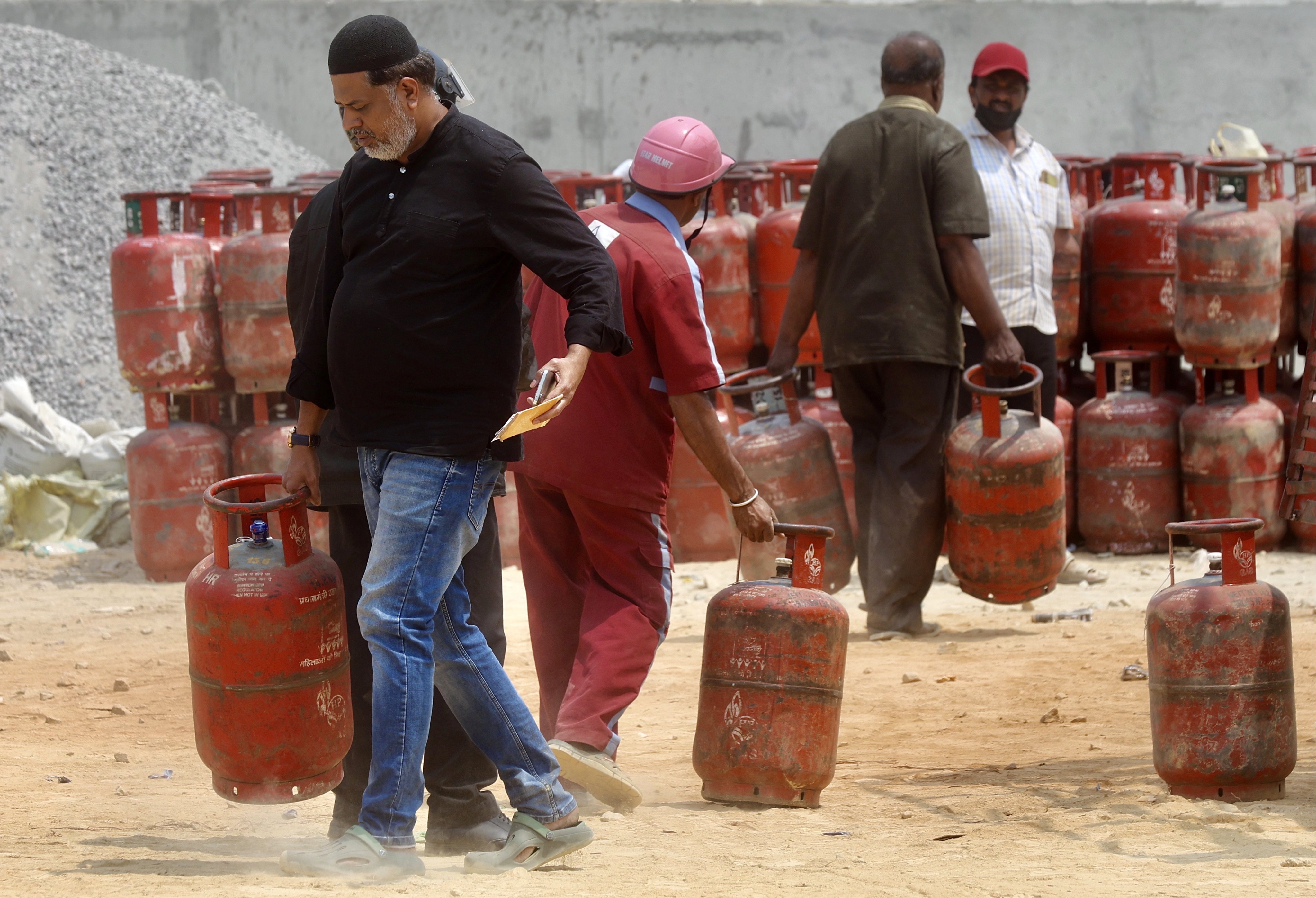 Customers carry empty LPG cylinders to exchange for refilled ones at a gas agency office in Bengaluru, India, on Monday. Photo: EPA