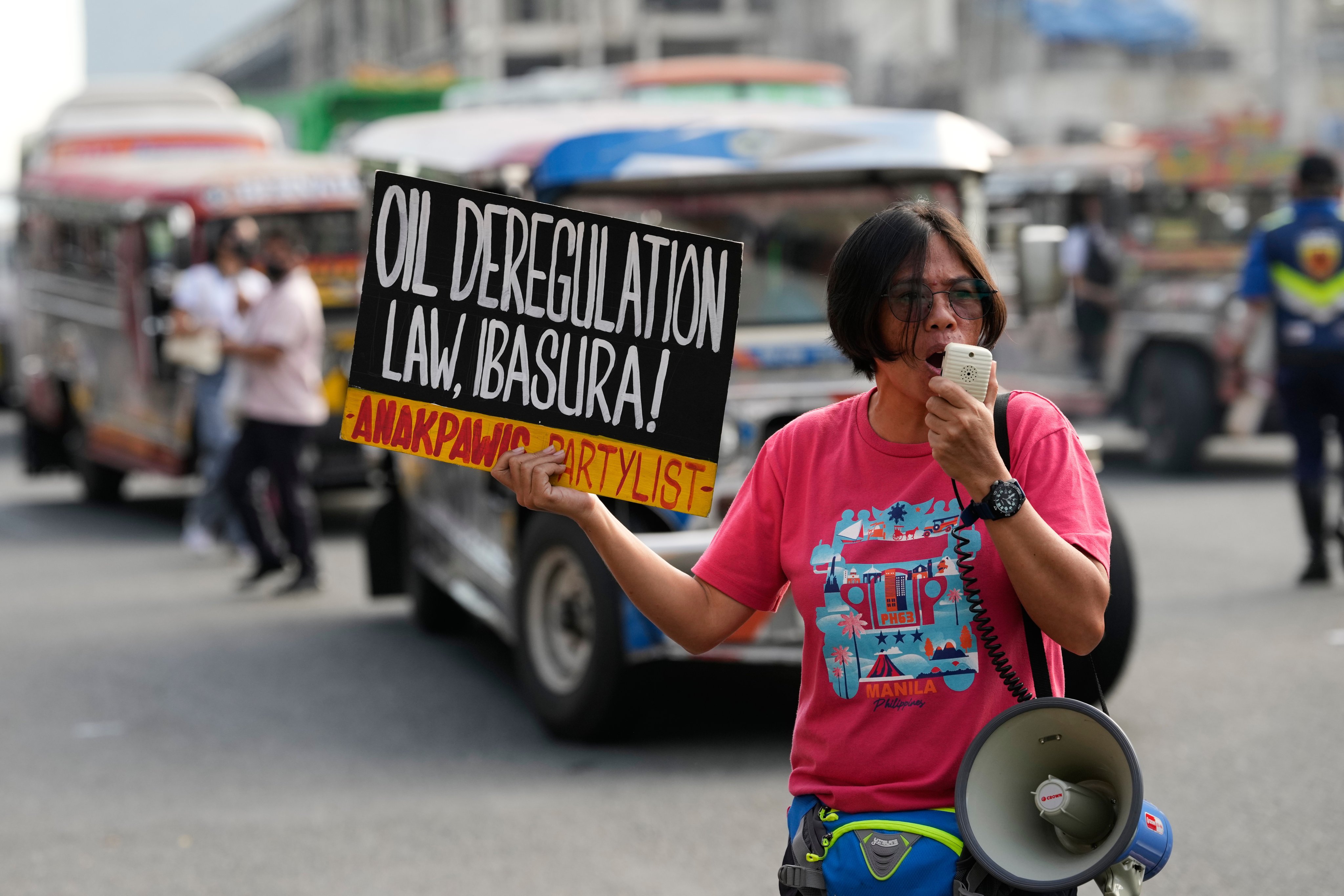 A protester holds a slogan that reads “scrap the oil deregulation law” as  jeepney drivers hold a transport strike in Quezon City on Thursday. Photo: AP