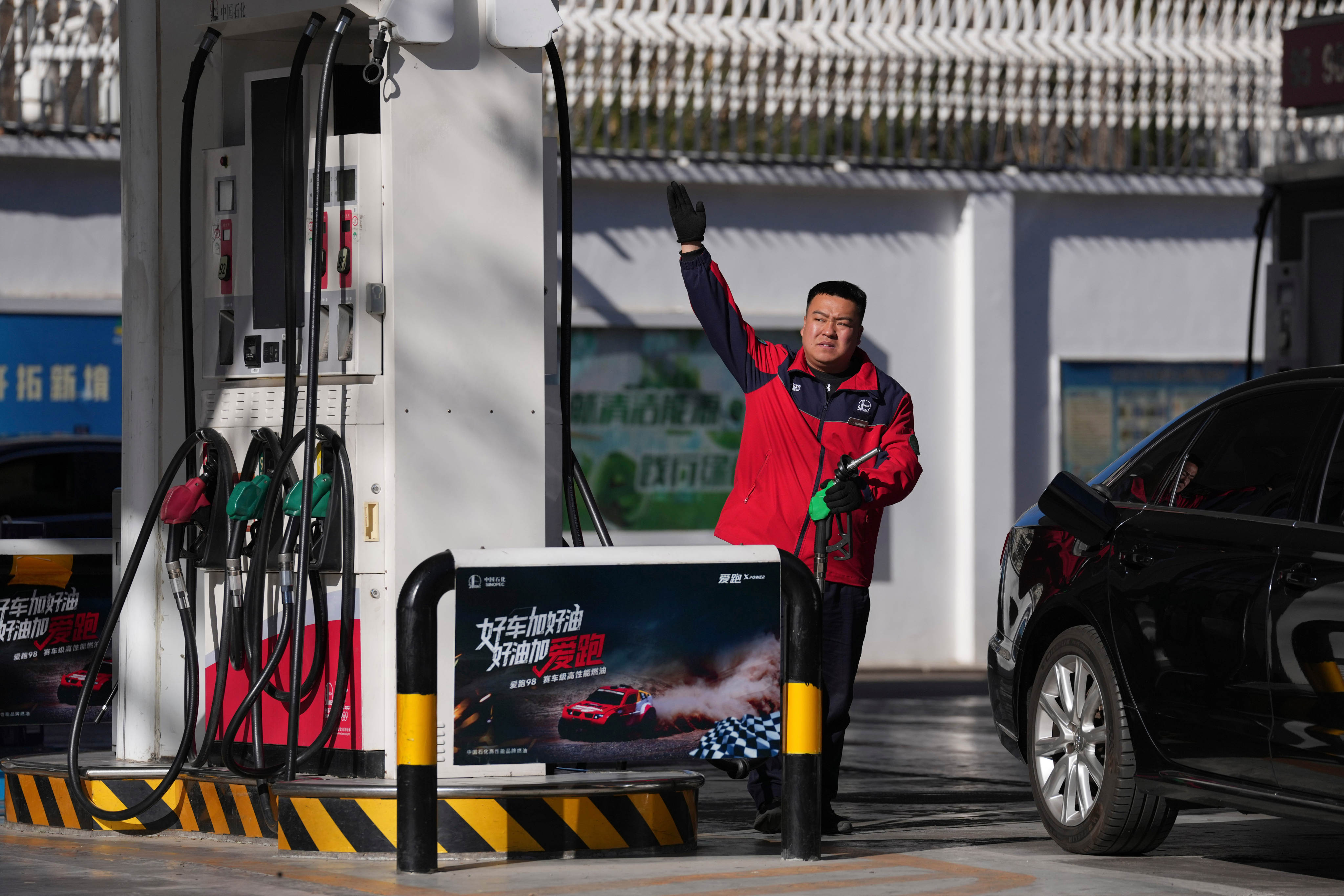 A petrol station attendant gestures in Beijing on March 11. Photo: AP