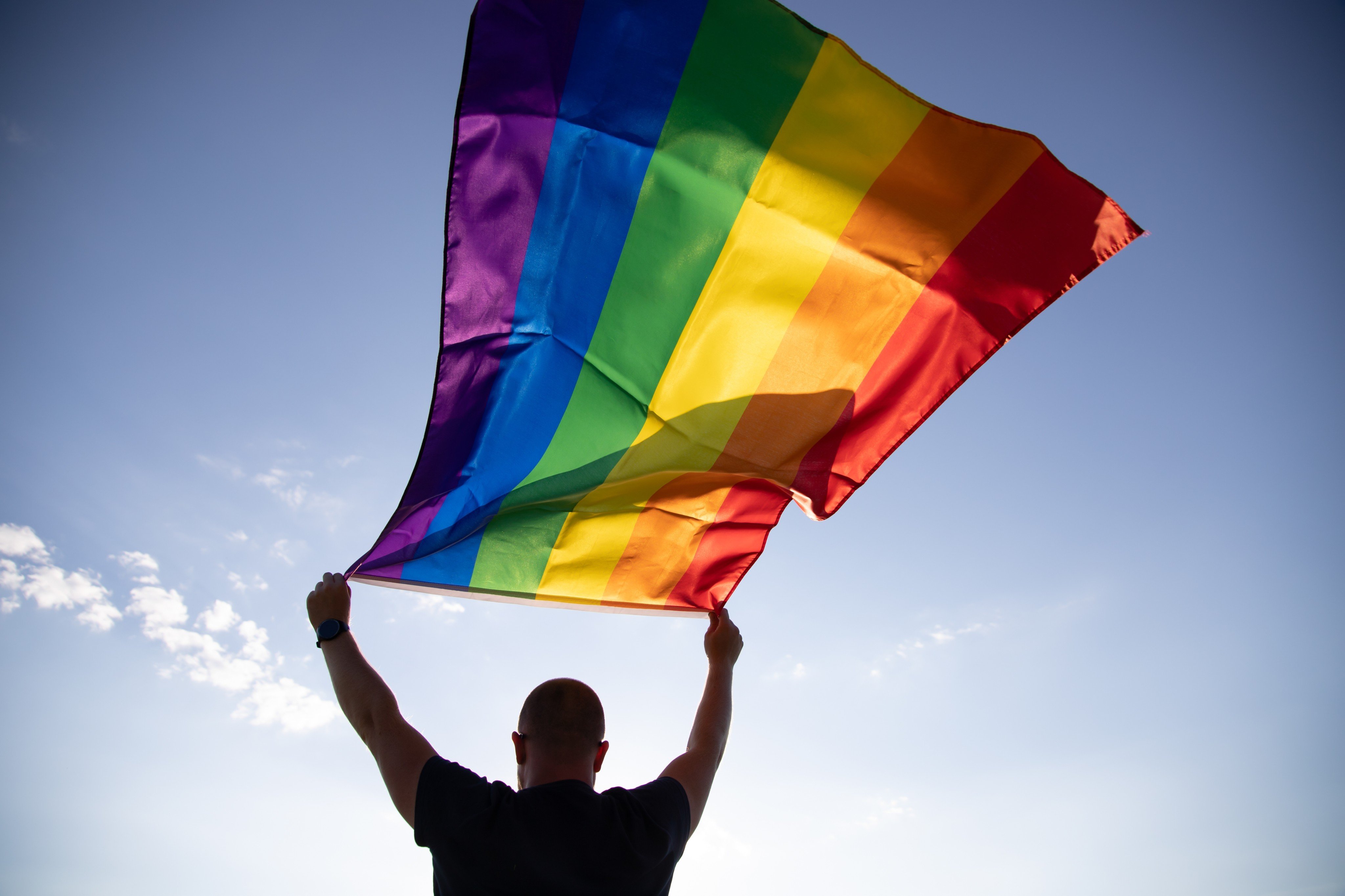 A man holds a rainbow flag, commonly used to signal LGBTQ pride. Photo: Shutterstock