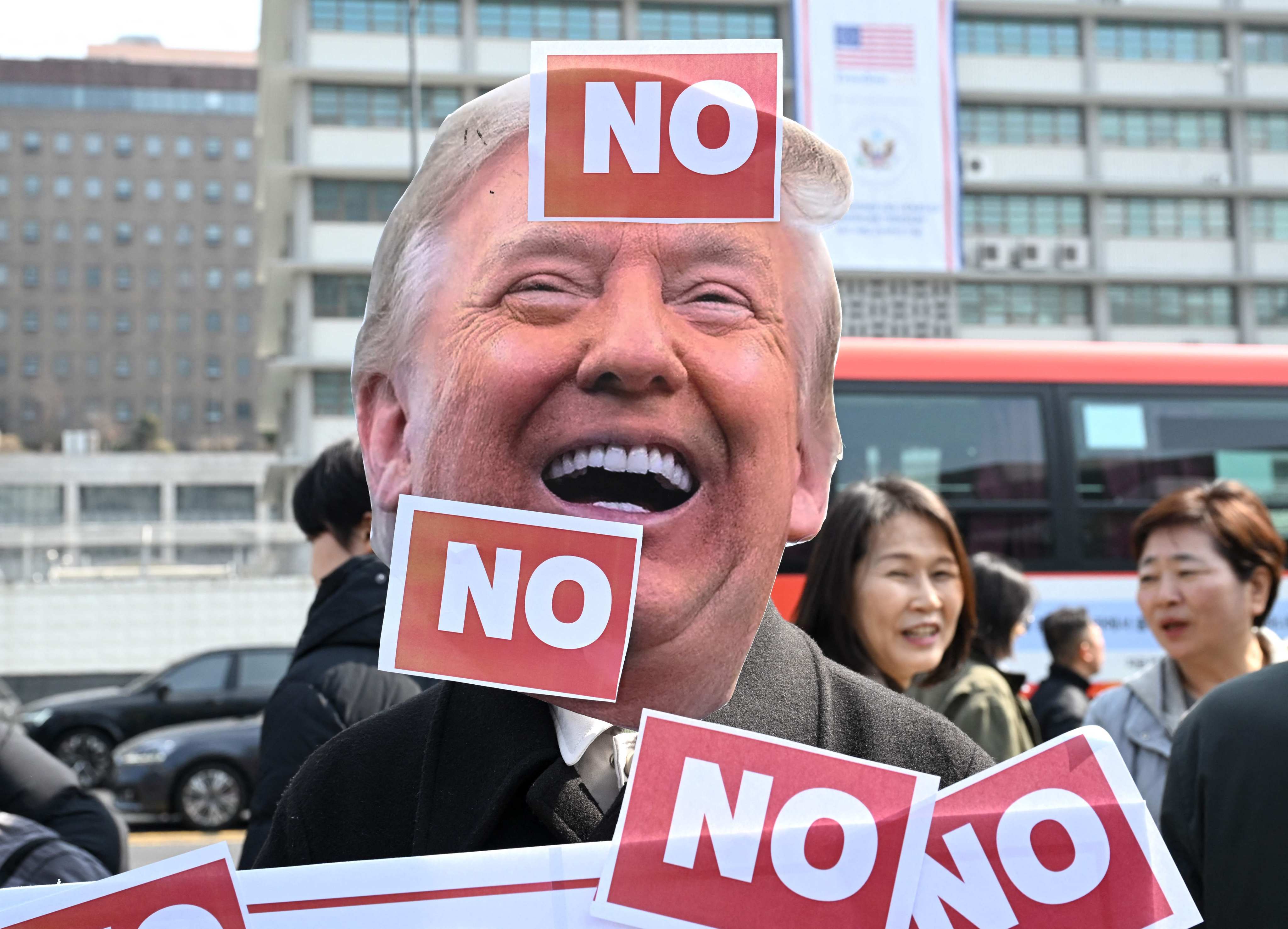 A protester wears a mask of US President Donald Trump in front of the US embassy in Seoul, South Korea, on March 16, during a demonstration against Trump’s request to dispatch warships to the Strait of Hormuz. Photo: AFP