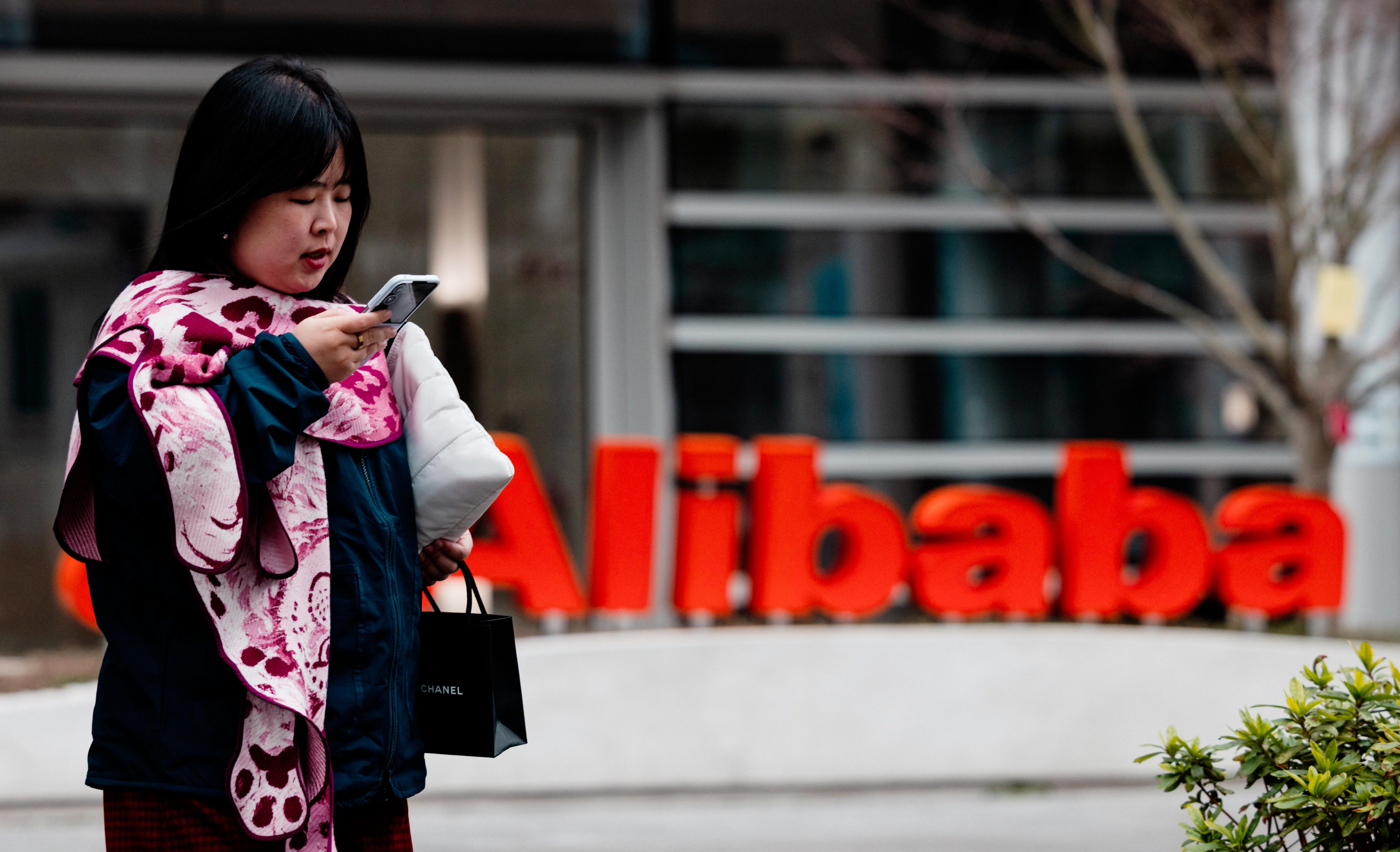 A woman walks past the Alibaba logo on its building in Xuhui Binjiang Park, also known as AI Park, in Shanghai, on March 19, 2026.  Photo: EPA