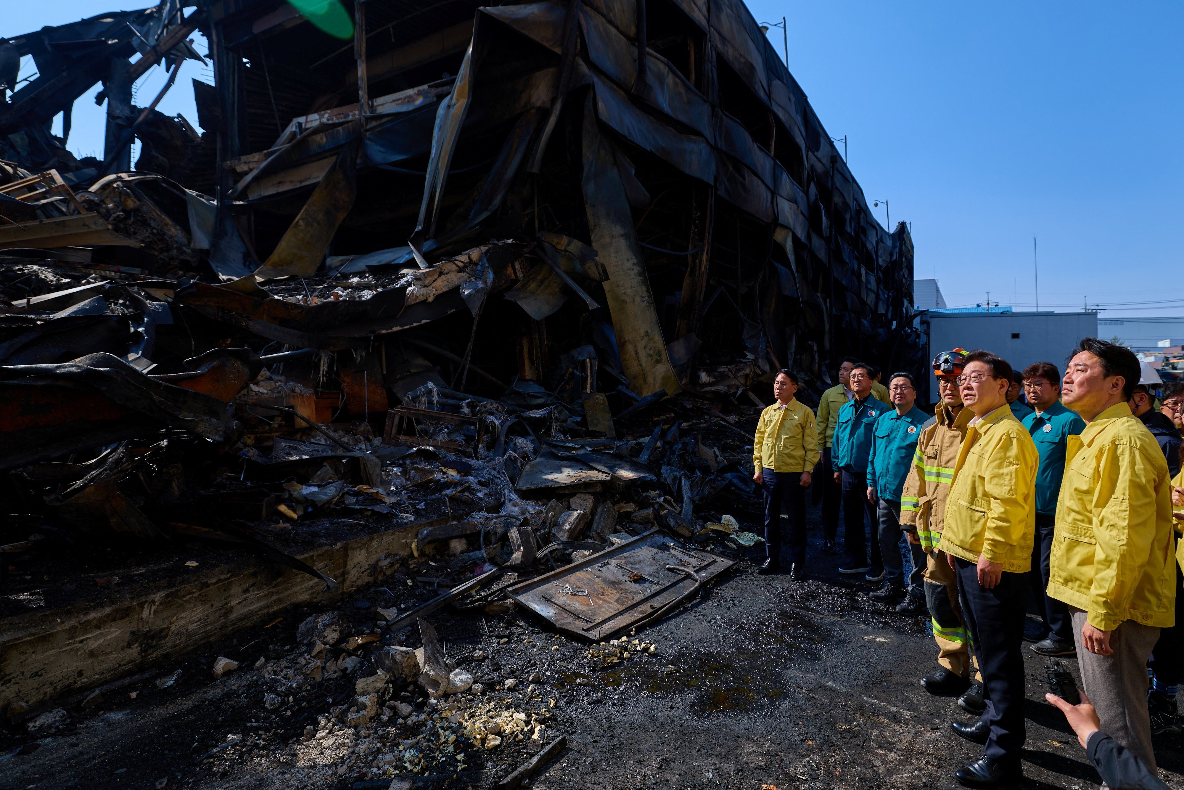South Korean President Lee Jae Myung and other officials inspect what remains of a factory in Daejeon on Saturday, after a huge fire that killed 14 people. Photo: via  Reuters