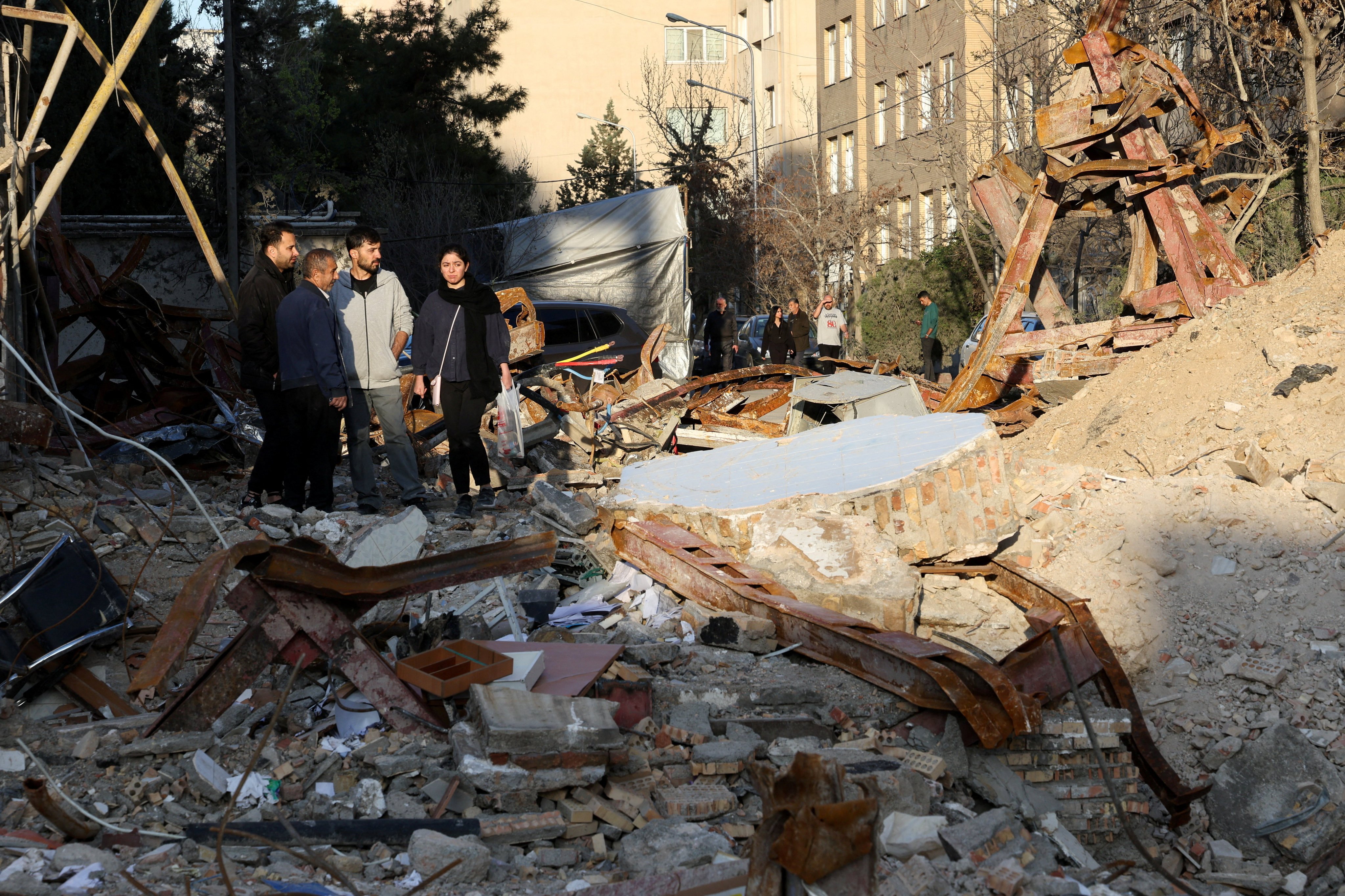 People look at a destroyed building in Tehran, following a strike amid the US-Israeli conflict with Iran, on March 21. Photo: Reuters