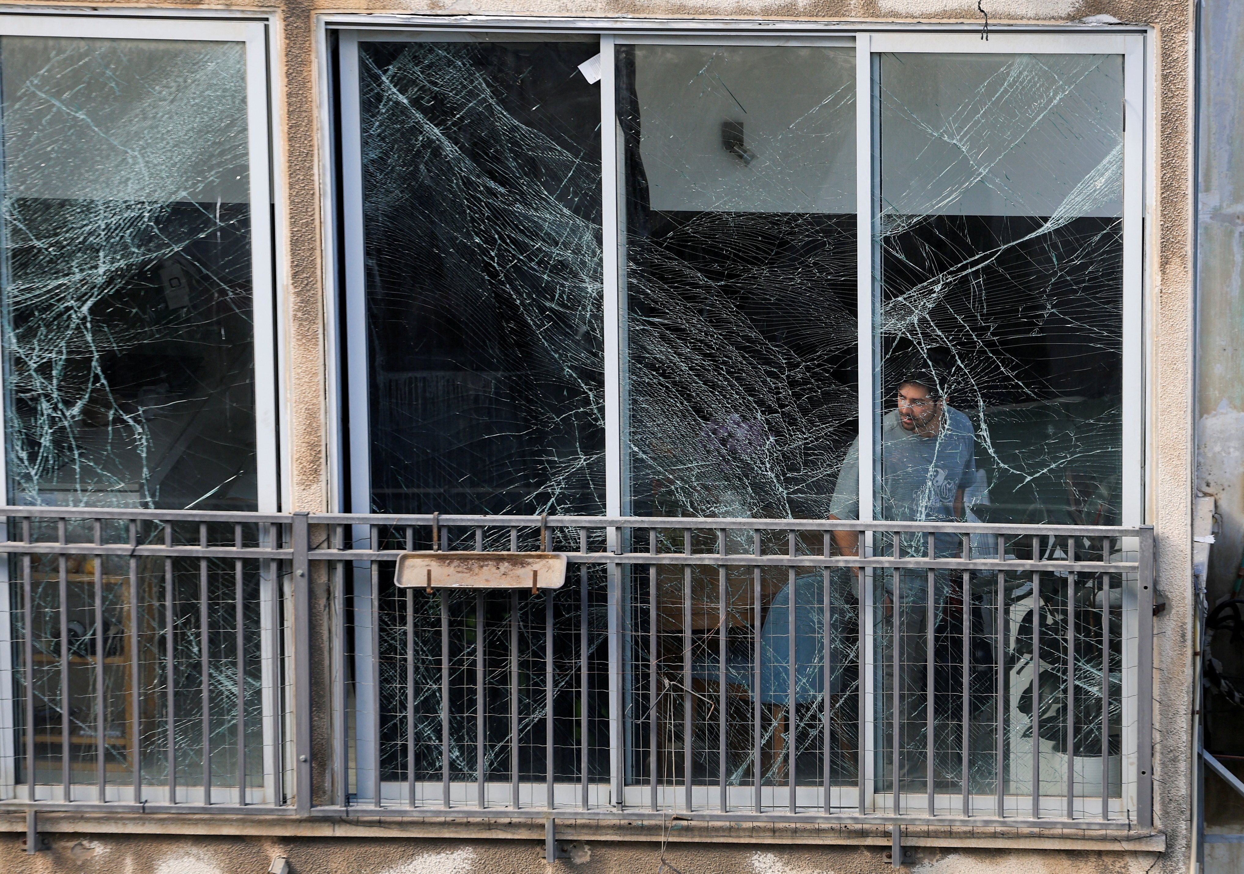 A man looks out of the window of a damaged building in Tel Aviv following Iranian missile barrages targeting central Israel. Photo: Reuters