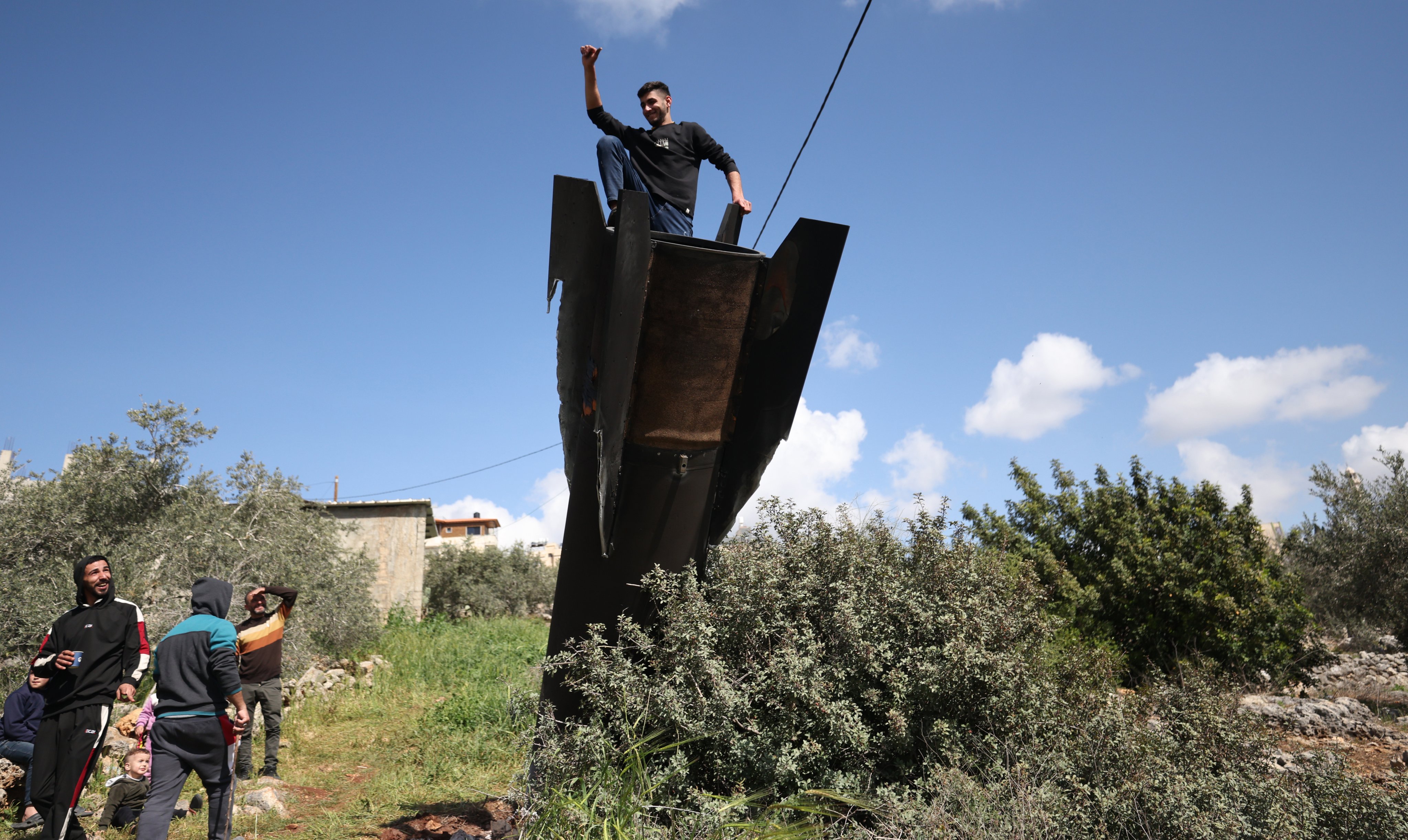 A Palestinian man climbs on the remains of a ballistic missile that landed in the West Bank village of Haris, near Salfit. Photo: EPA