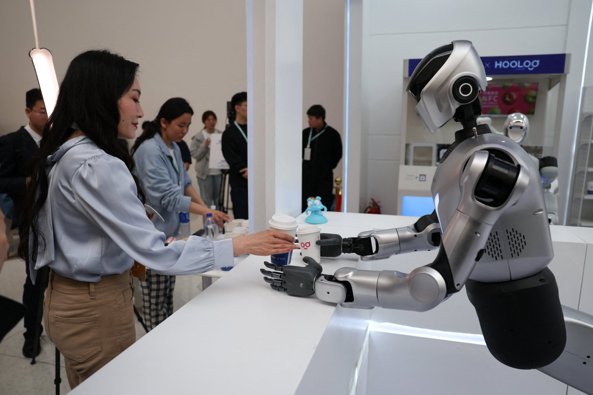 A Kuavo-5W humanoid robot by Leju Robotics passes freshly made coffee to a journalist during a demonstration at the 2026 Zhongguancun Forum, a major annual technology conference in Beijing on March 25. Photo: Reuters