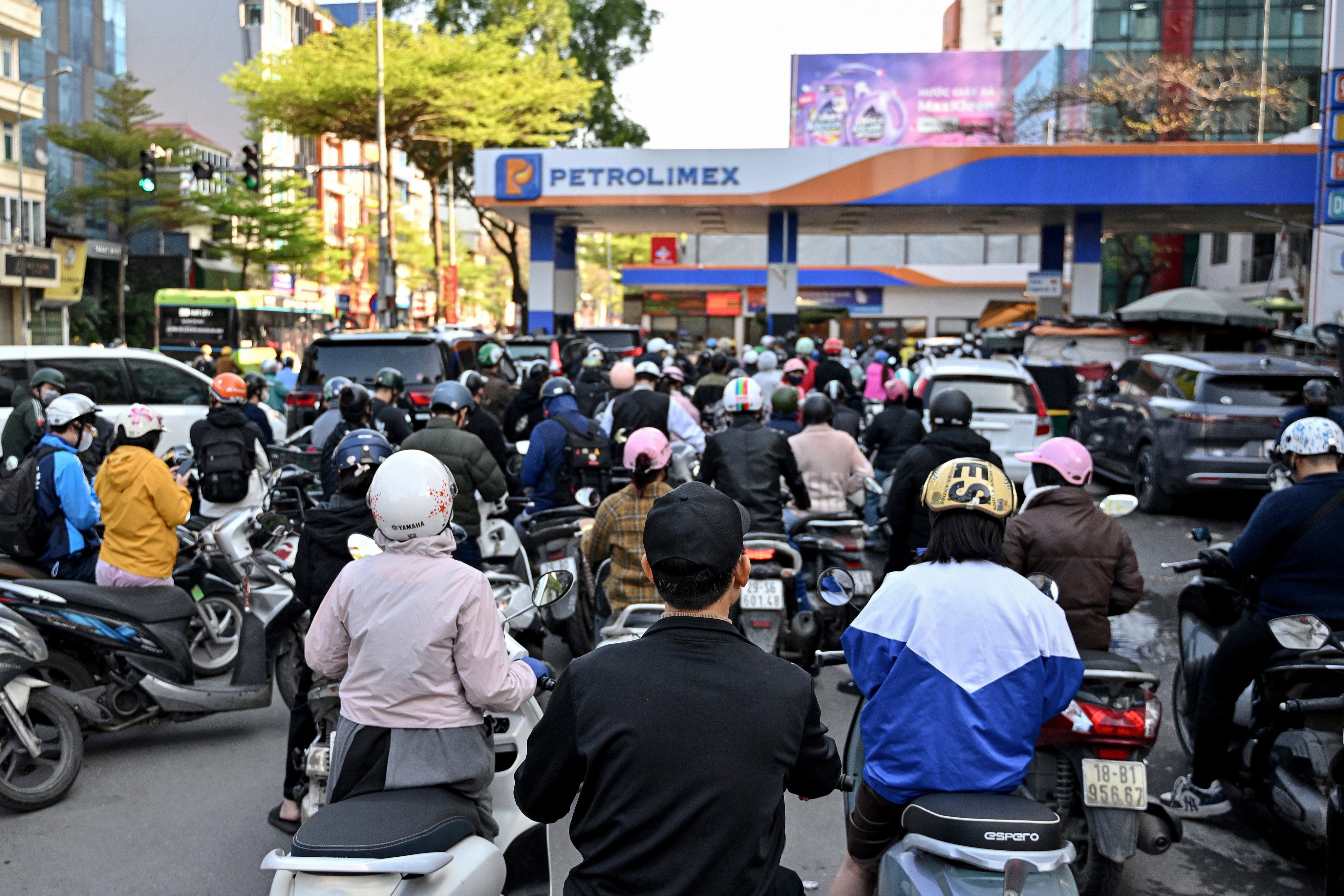 Motorists queue to pump gasoline into their vehicle at a gas station in Hanoi on March 10, 2026. Vietnam announced on March 9 it was scrapping tariffs on fuel imports, as the US-Israeli war with Iran disrupts oil supplies and pushes prices to their highest level since 2022. (Photo by Nhac NGUYEN / AFP)