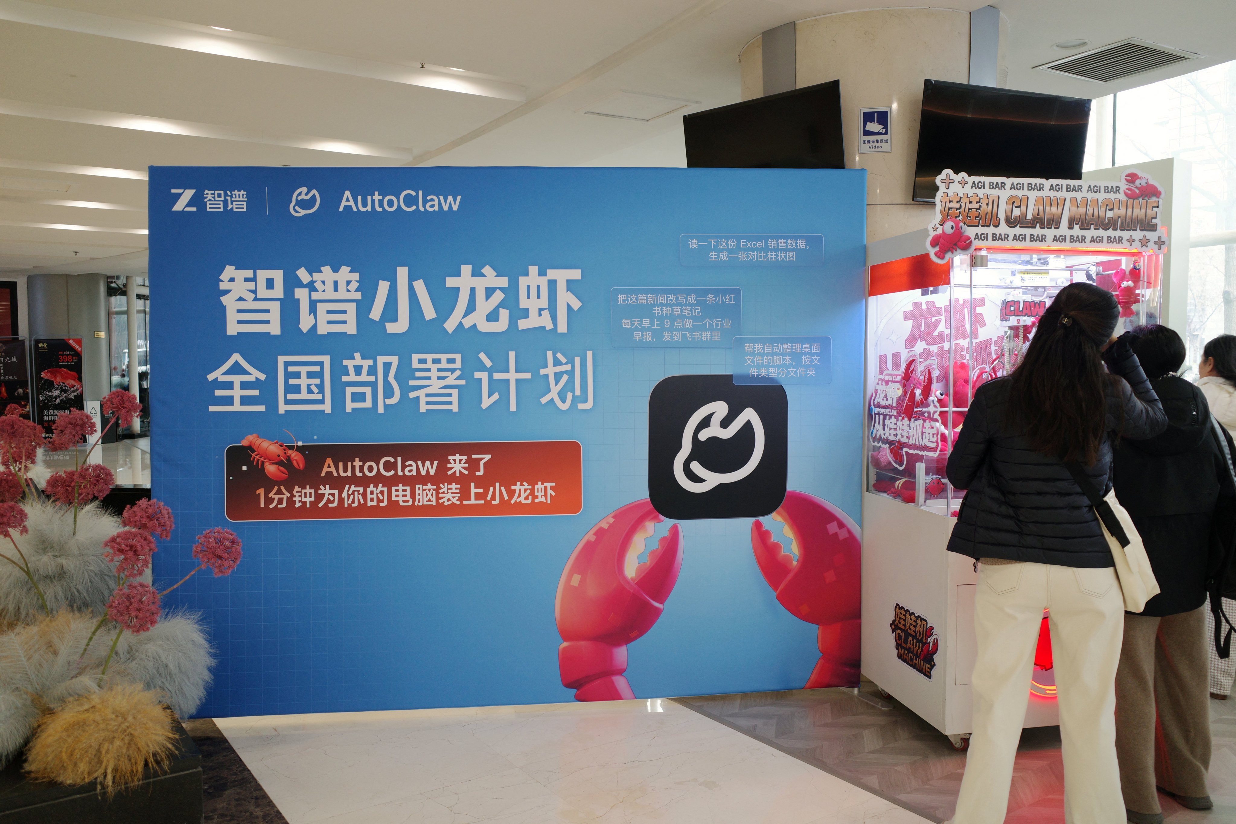 People stand in front of a claw machine filled with lobster-shaped plush toys during a setup session for AutoClaw, a local version of the AI agent OpenClaw, in Beijing. Photo: Reuters