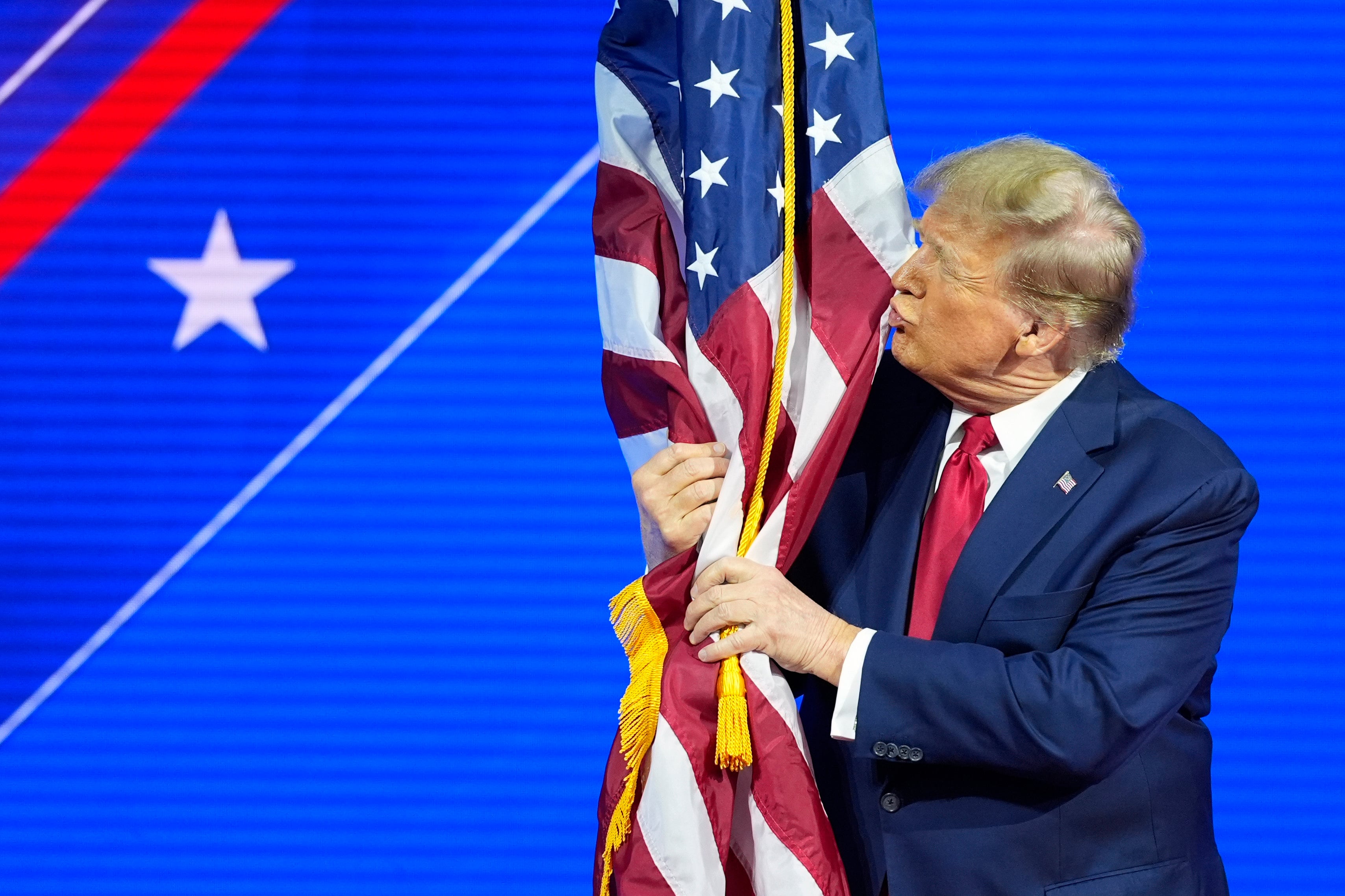 Donald Trump hugs and kisses the American flag at CPAC 2024. Photo: AP
