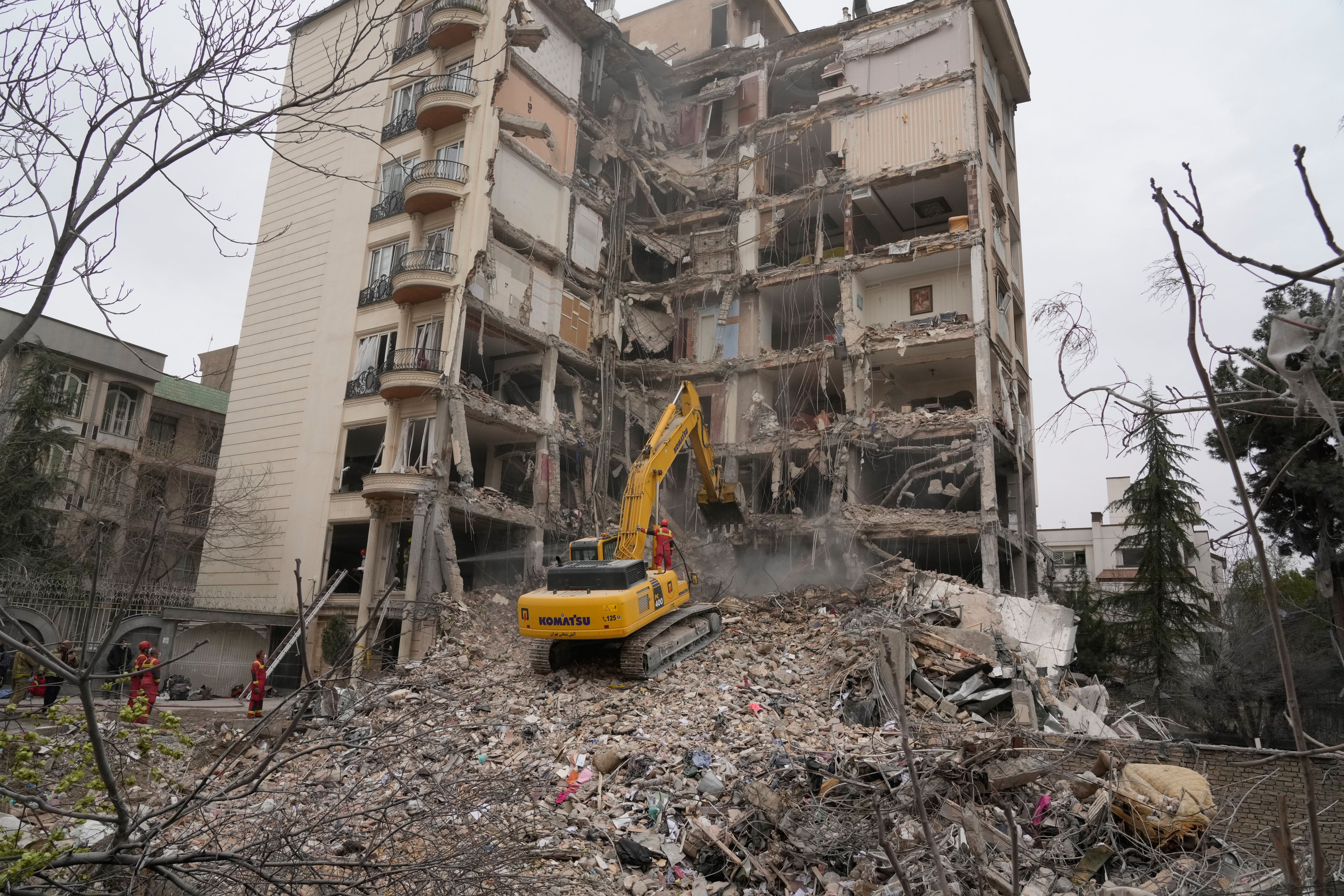 Iranian firefighters use an excavator to clear rubble from a residential building that was hit in an earlier US-Israeli strike in Tehran, on March 23. Photo: AP