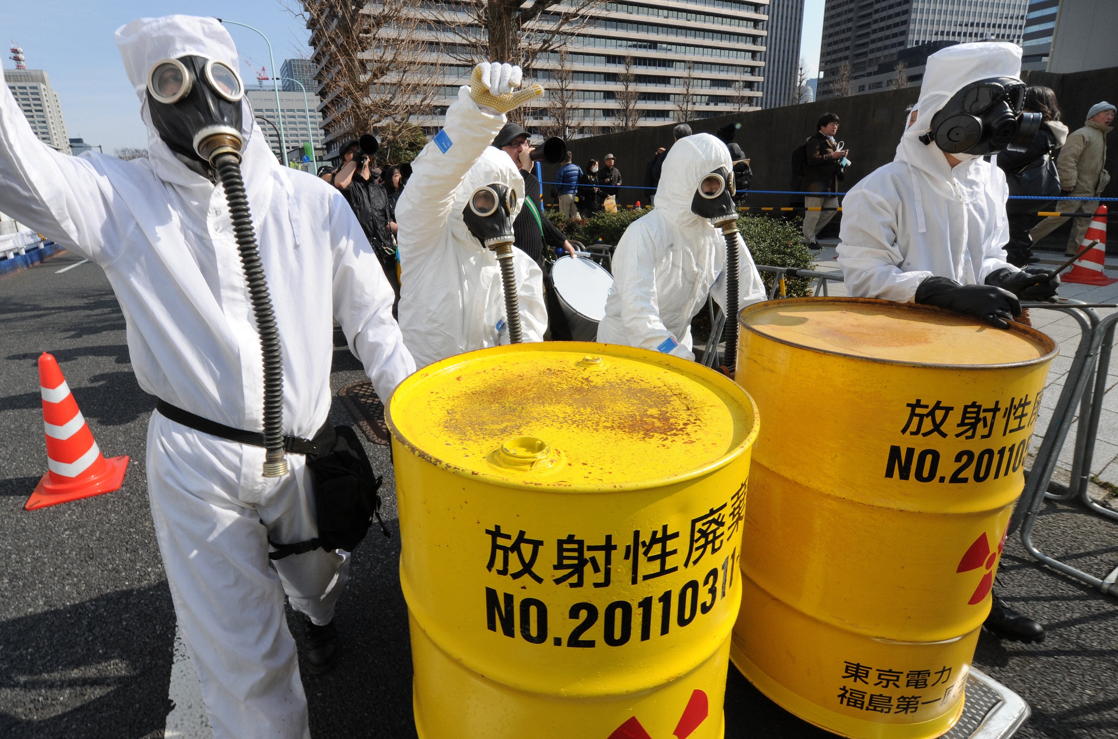 Protesters wearing protective suits and masks shout slogans next to mock drums of nuclear waste during a rally in Tokyo. Photo: AFP