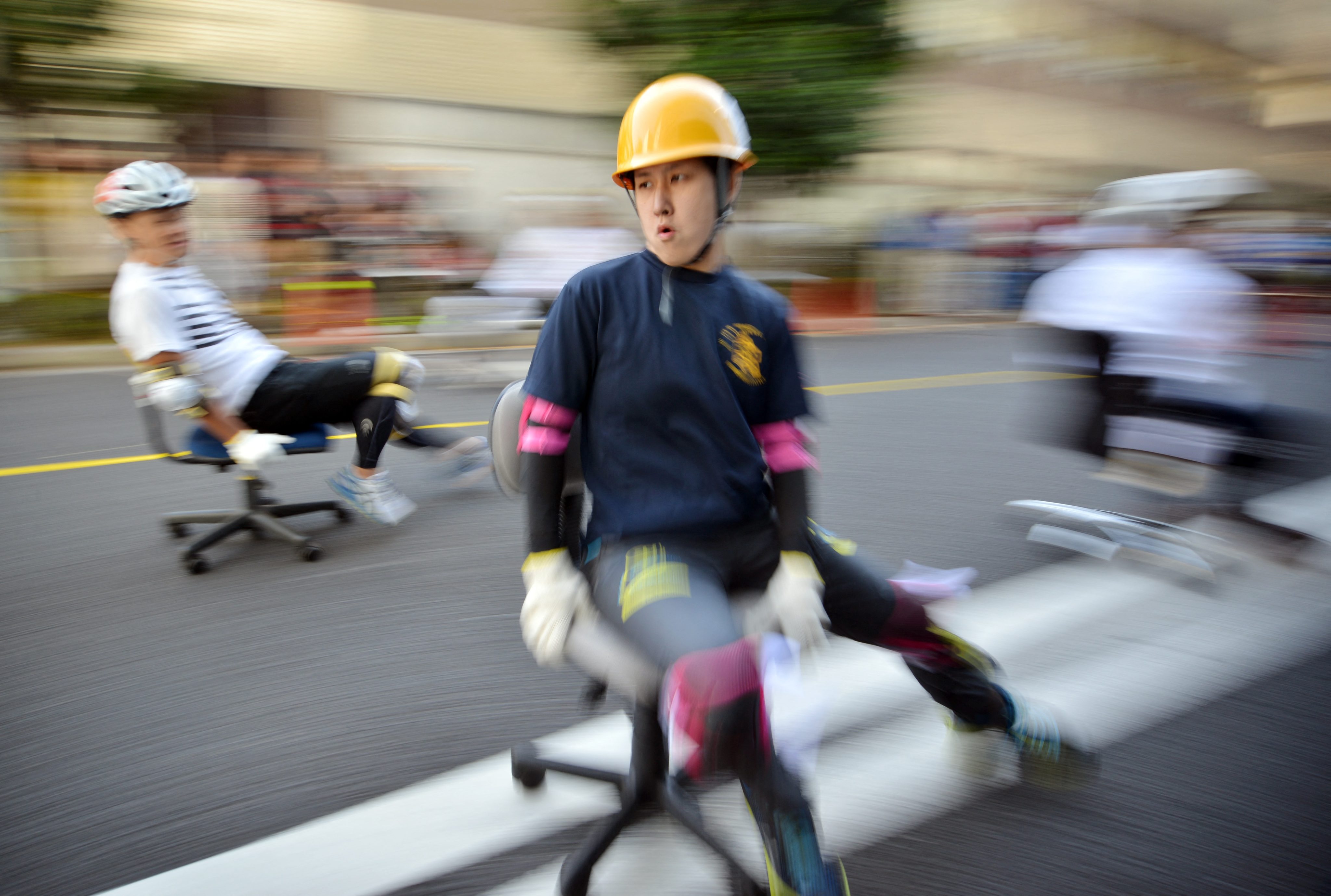 Office workers negotiate a corner during an office chair race, called “Isu-one Grand Prix” (Chair-one Grand Prix), in Tokyo’s Kyobashi business district on October 25, 2015. 31 teams, each with three members, competed in a two-hour endurance race with office chairs on October 25. AFP PHOTO / Yoshikazu TSUNO (Photo by YOSHIKAZU TSUNO / AFP)