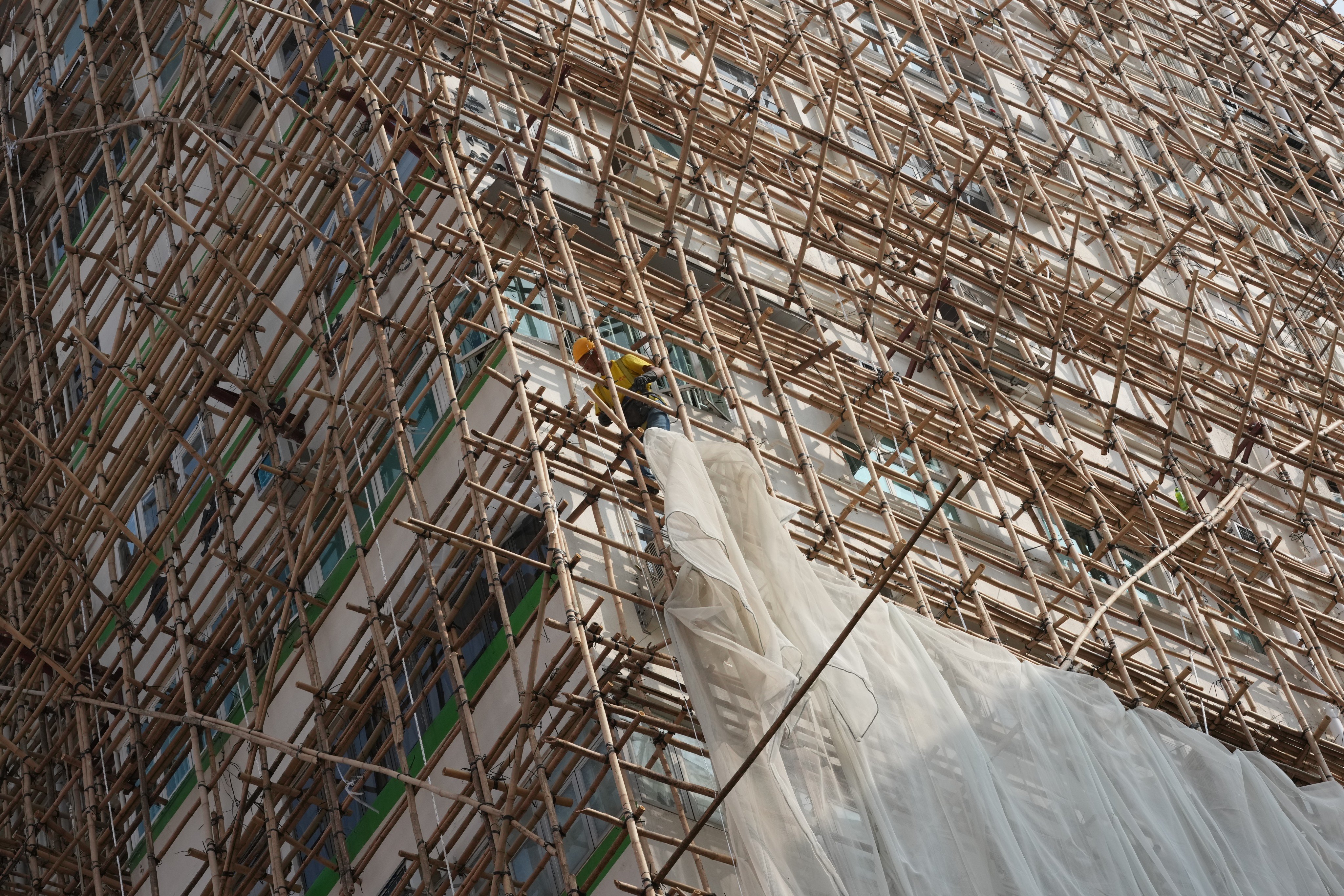 A worker removes scaffolding mesh on a building in Mong Kok. Photo: Jelly Tse