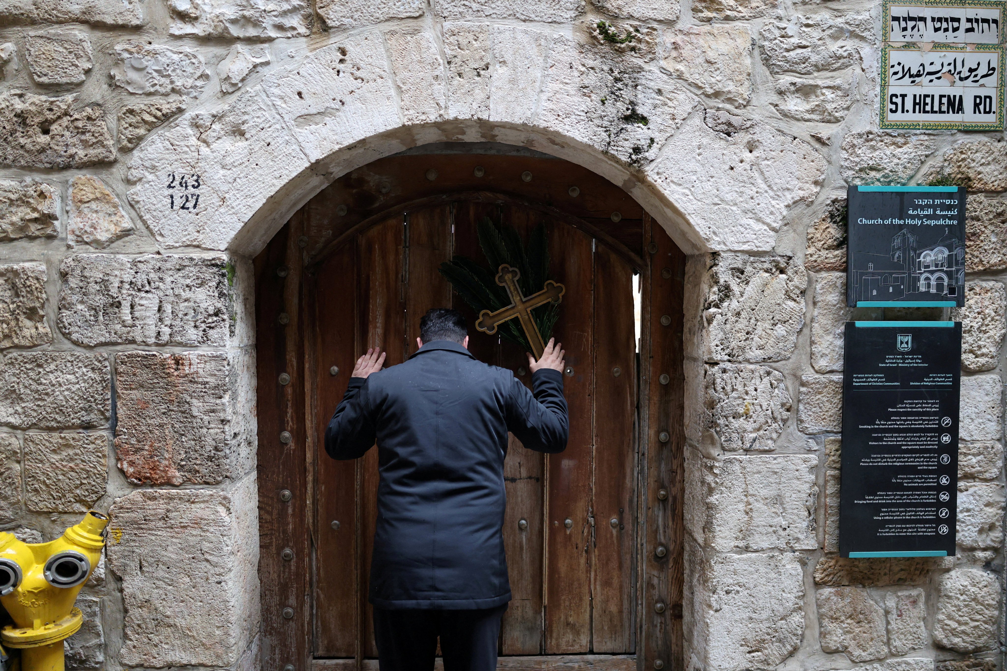 Issa Kassissieh, a Palestinian Christian, holds a cross and a palm frond while standing at the doors of the Church of the Holy Sepulchre in Jerusalem after finding them locked on Palm Sunday. Photo: Reuters