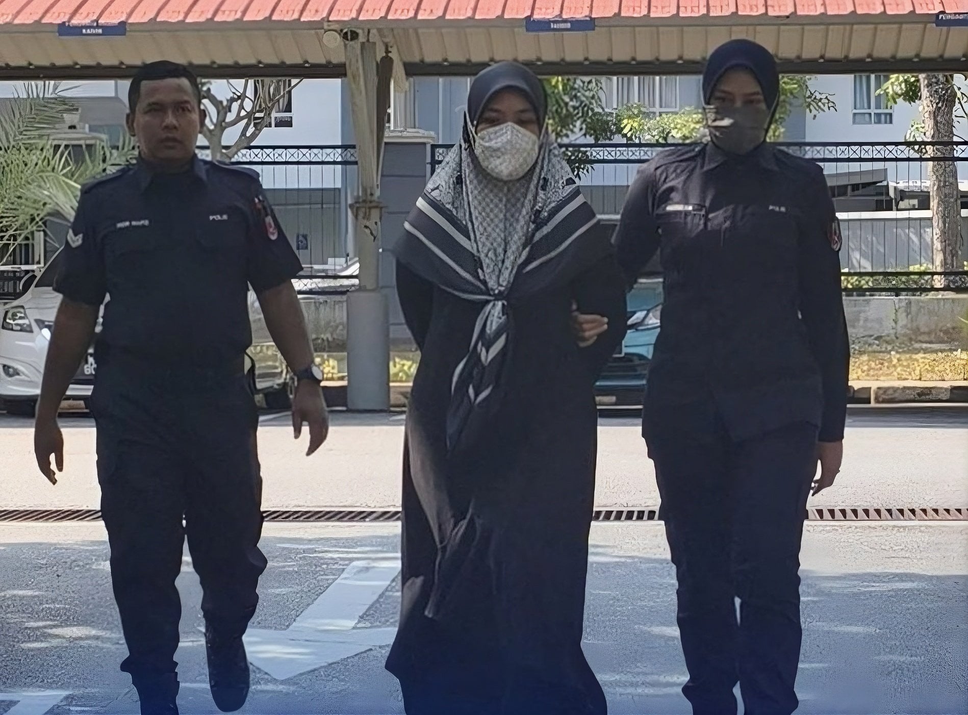 Khairunnisa Ahmad Damamhuri being escorted by police officers. Photo: The Star