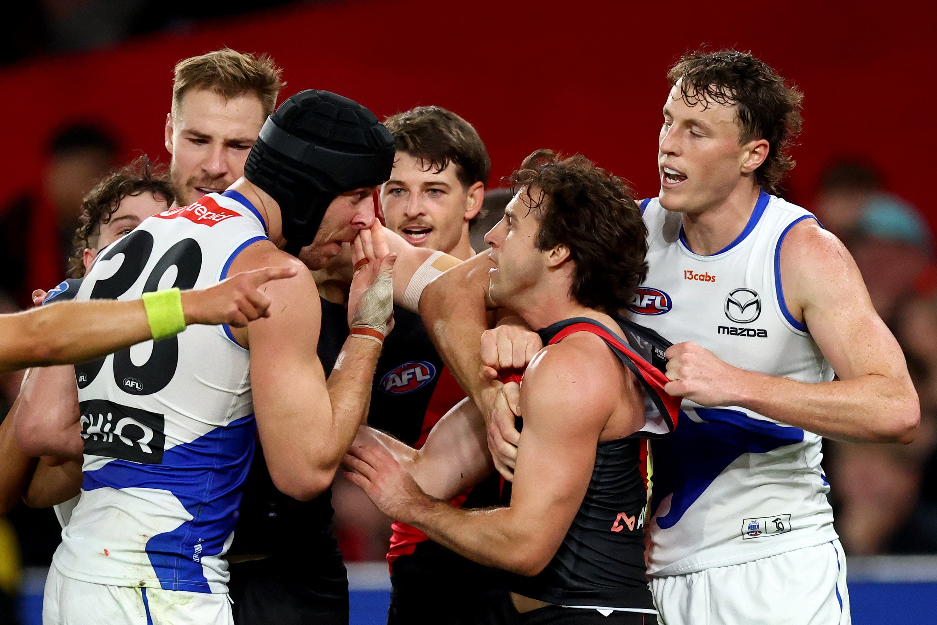 Tristan Xerri of the North Melbourne Kangaroos (left) about to wipe blood on the face of Essendon captain Andrew McGrath (second from right) in their AFL match at Marvel Stadium in Melbourne on Saturday. Photo: Getty Images